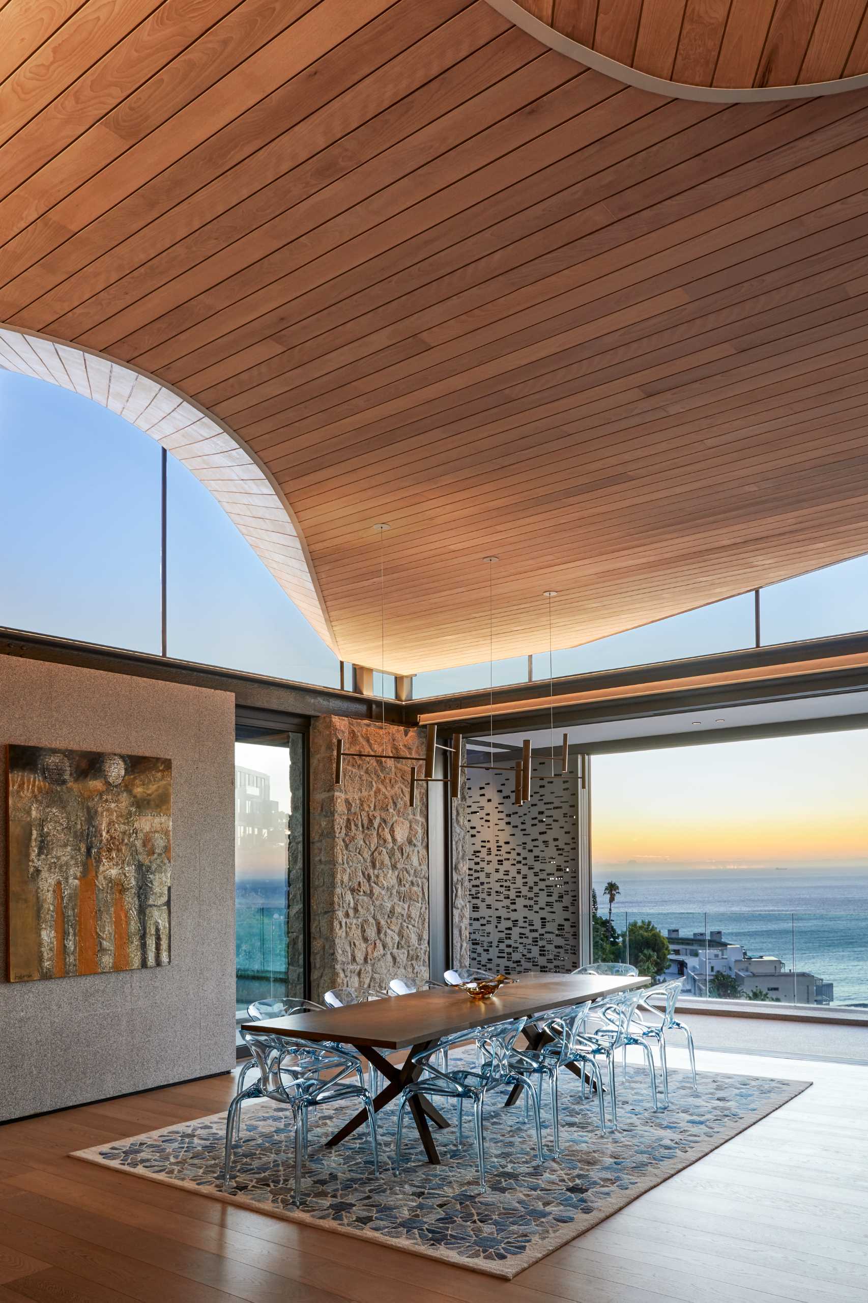 A modern dining area with clerestory windows and an undulating wood-lined ceiling.