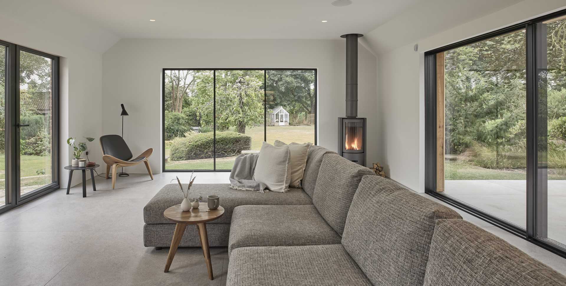 Inside this modern home extension, there's a lounge with a fireplace and windows that look out onto the garden.