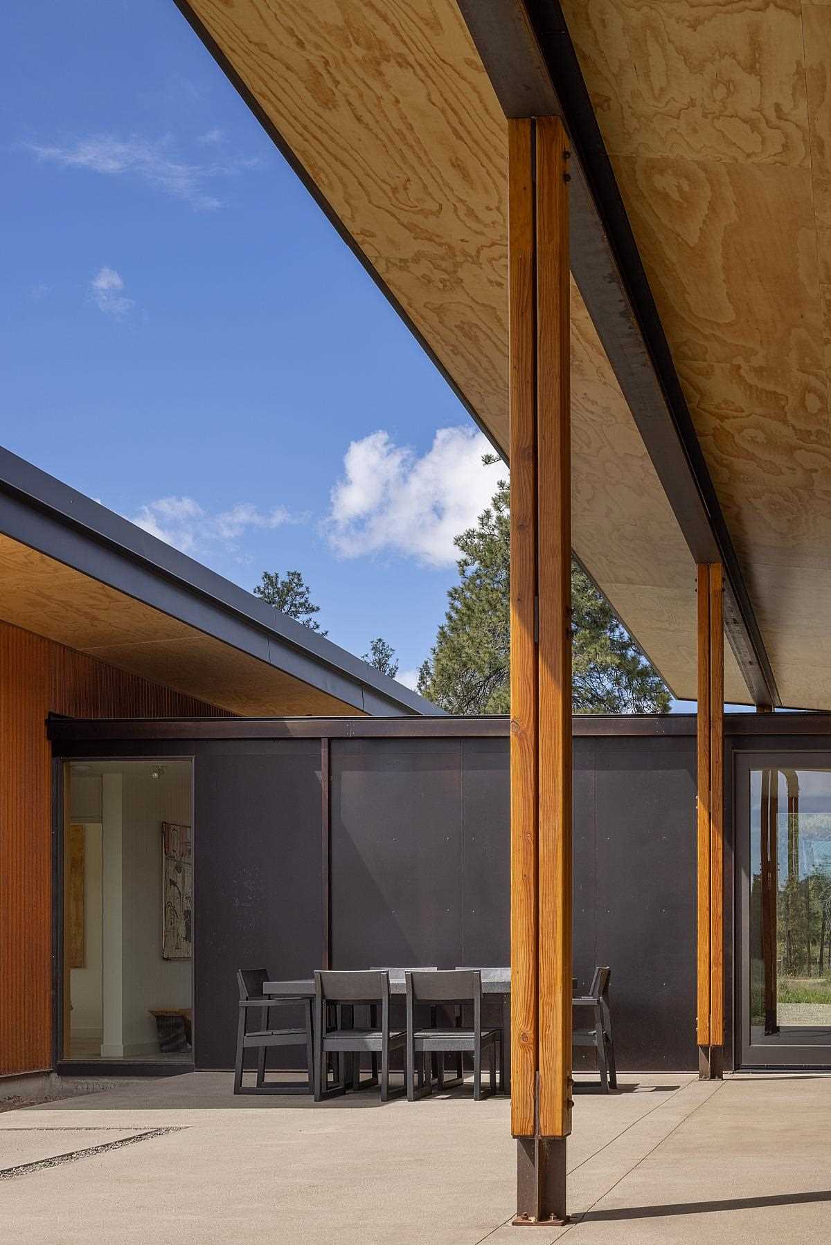 Between the two areas of this contemporary home is a partially covered patio with a dining area and an space for sitting around an outdoor fire.