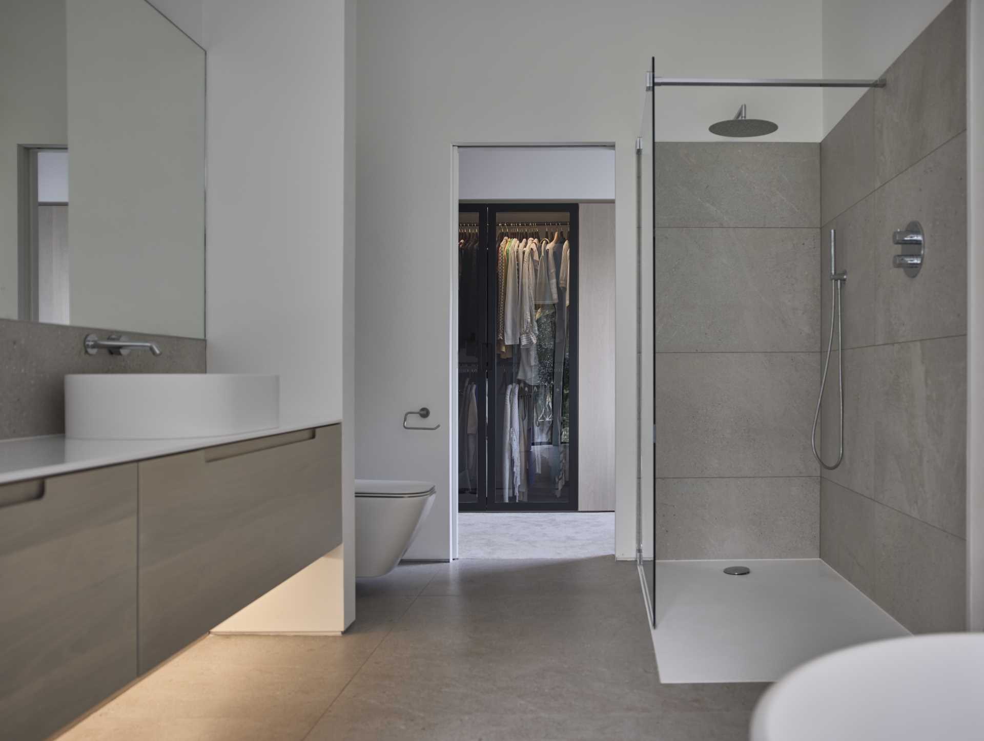 This modern en-suite bathroom becomes a room of serenity, enhanced by large corner window that immerses the space in natural light and offers expansive views of the garden.