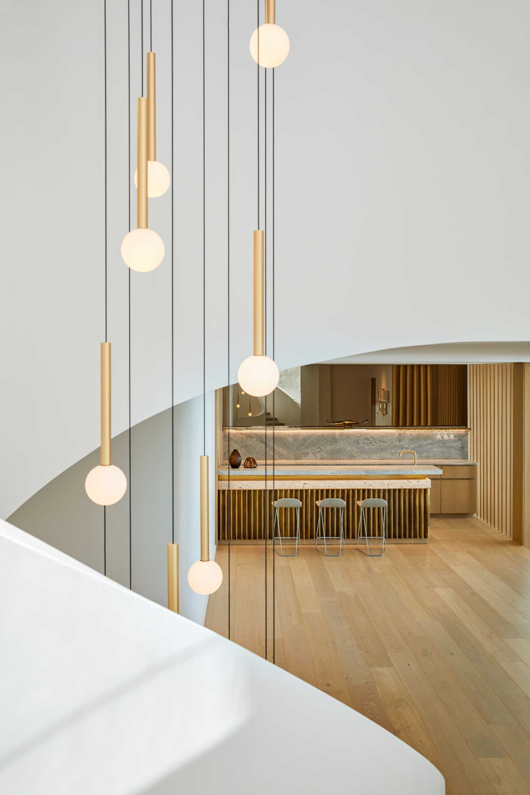 A modern home with a sculptural staircase that also includes pendant lights at varying heights.