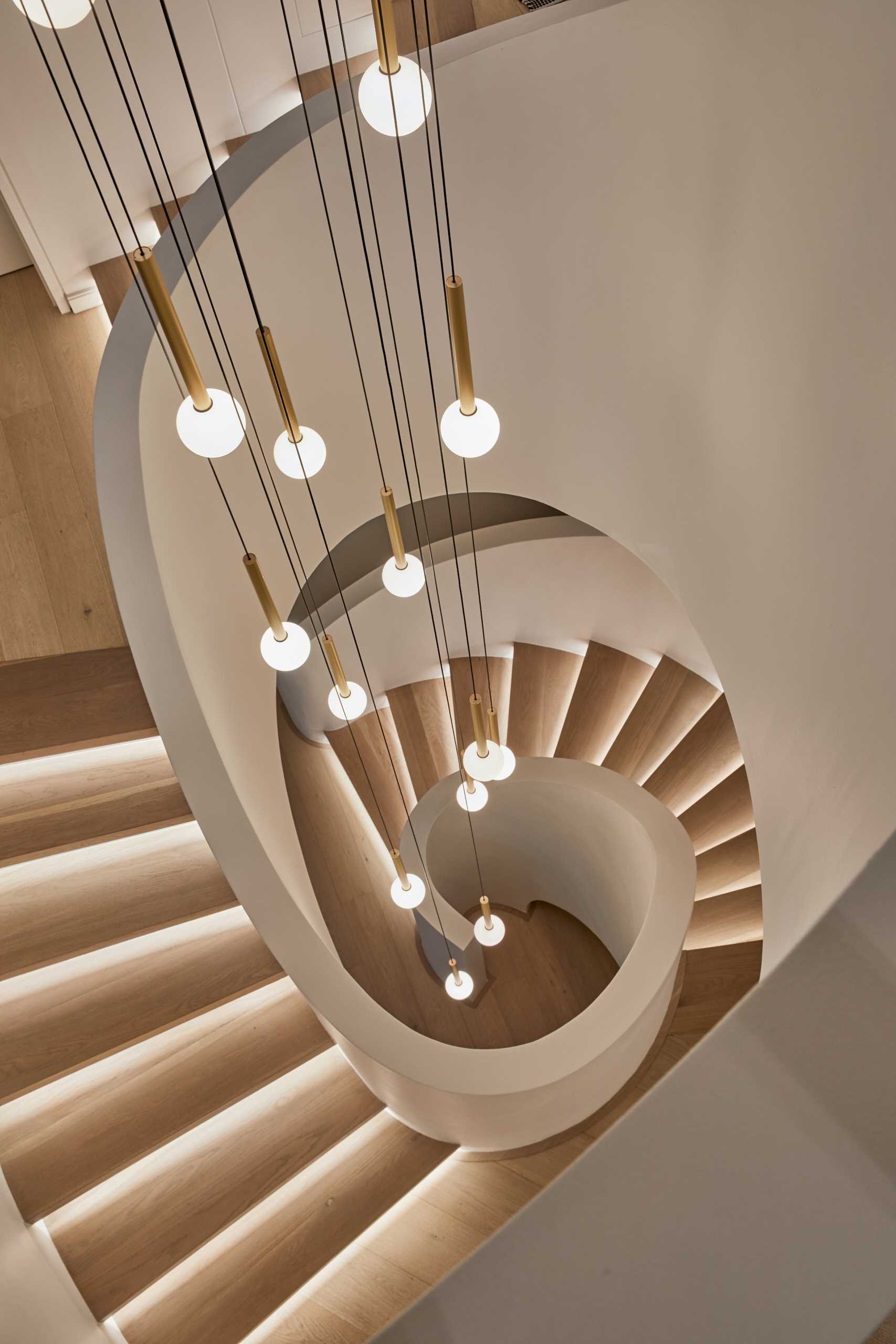 A modern home with a sculptural staircase that also includes pendant lights at varying heights.