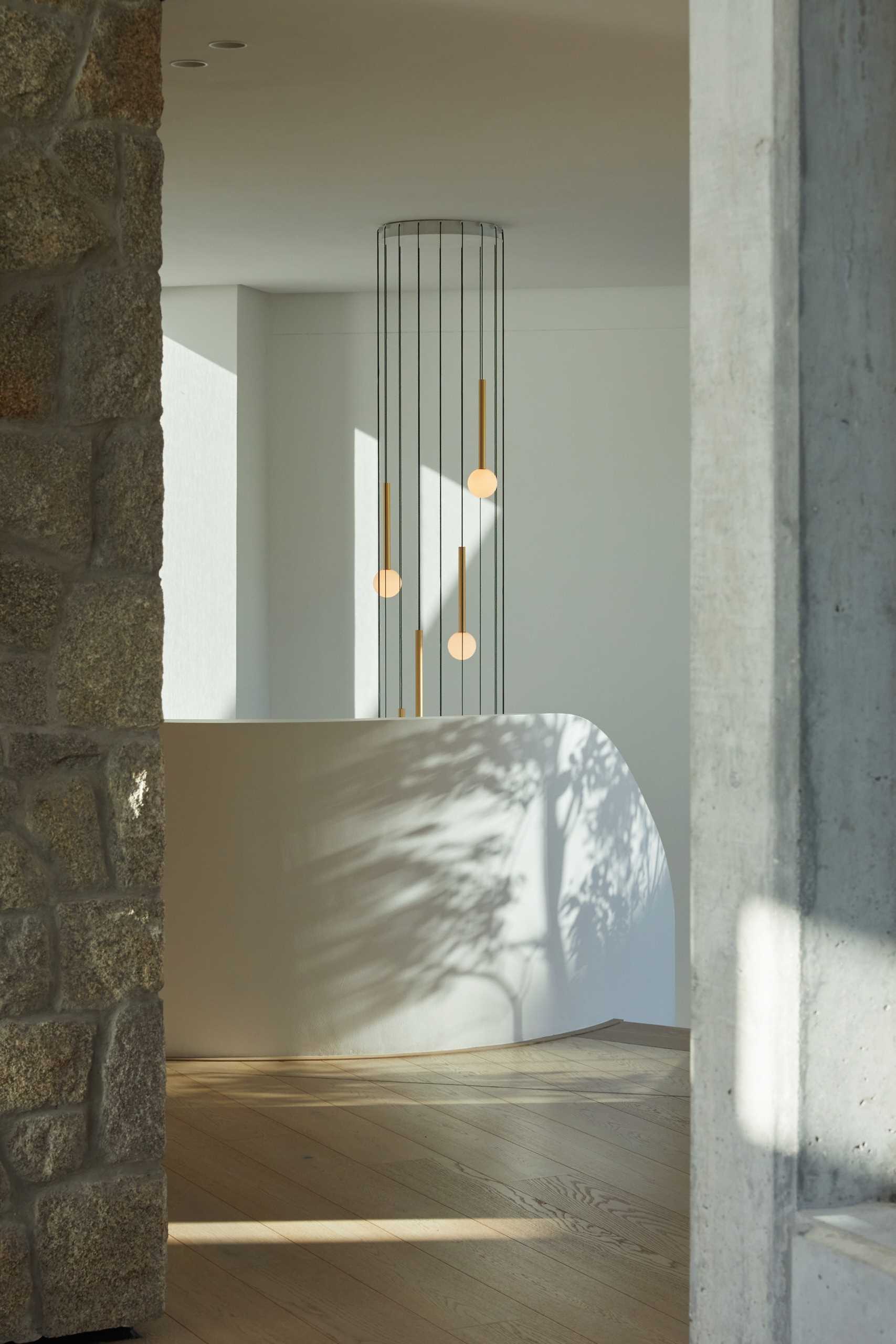 A modern home with a sculptural staircase that also includes pendant lights at varying heights.