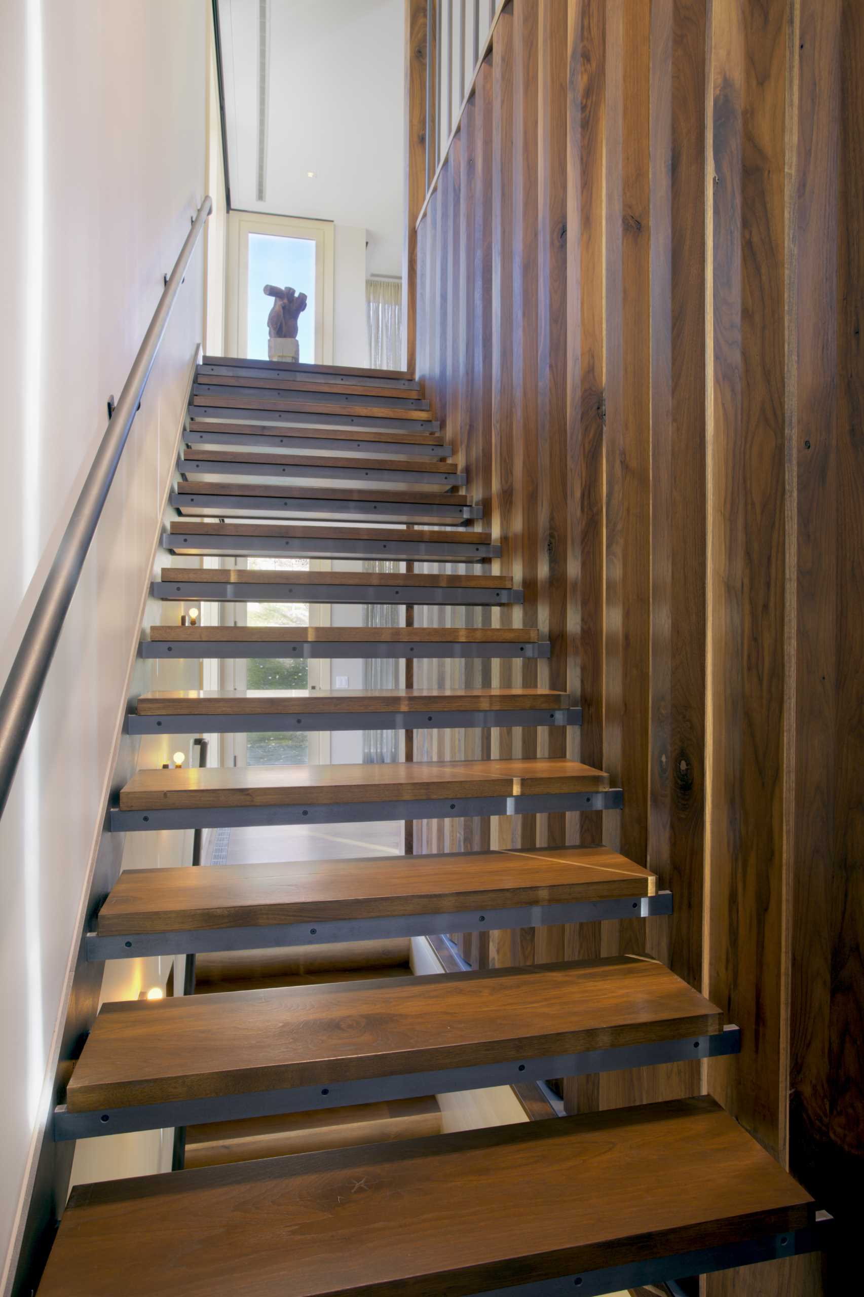 Wood and steel stairs connect the different levels of the home, and include a leather wrapped metal handrail that was crafted by a local saddle maker.