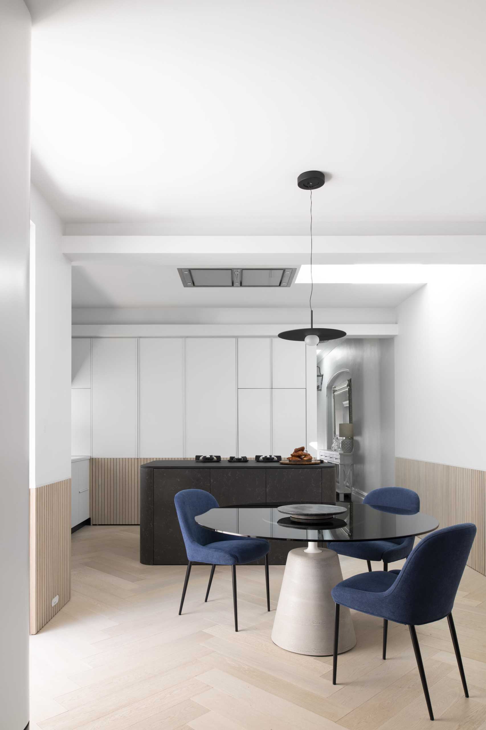 A modern white kitchen with wood paneling around the lower section of the cabinets. Integrated appliances have also been included in the kitchen design.