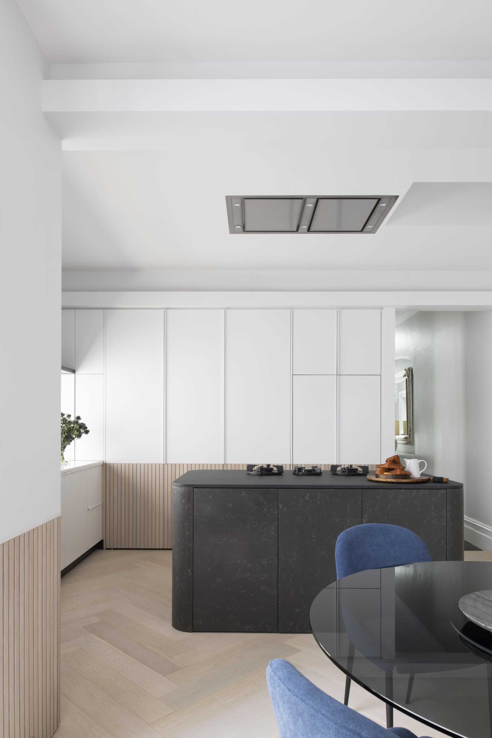 A modern white kitchen with wood paneling around the lower section of the cabinets. Integrated appliances have also been included in the kitchen design.