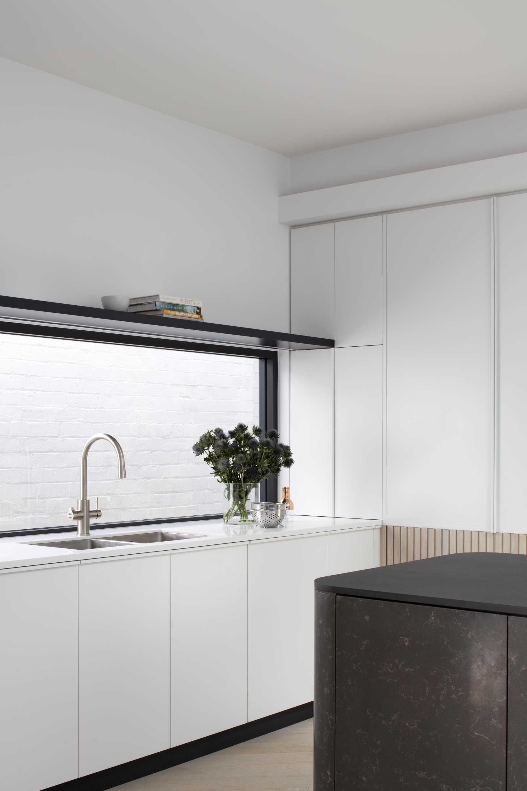 A modern white kitchen with wood paneling around the lower section of the cabinets. Integrated appliances have also been included in the kitchen design.