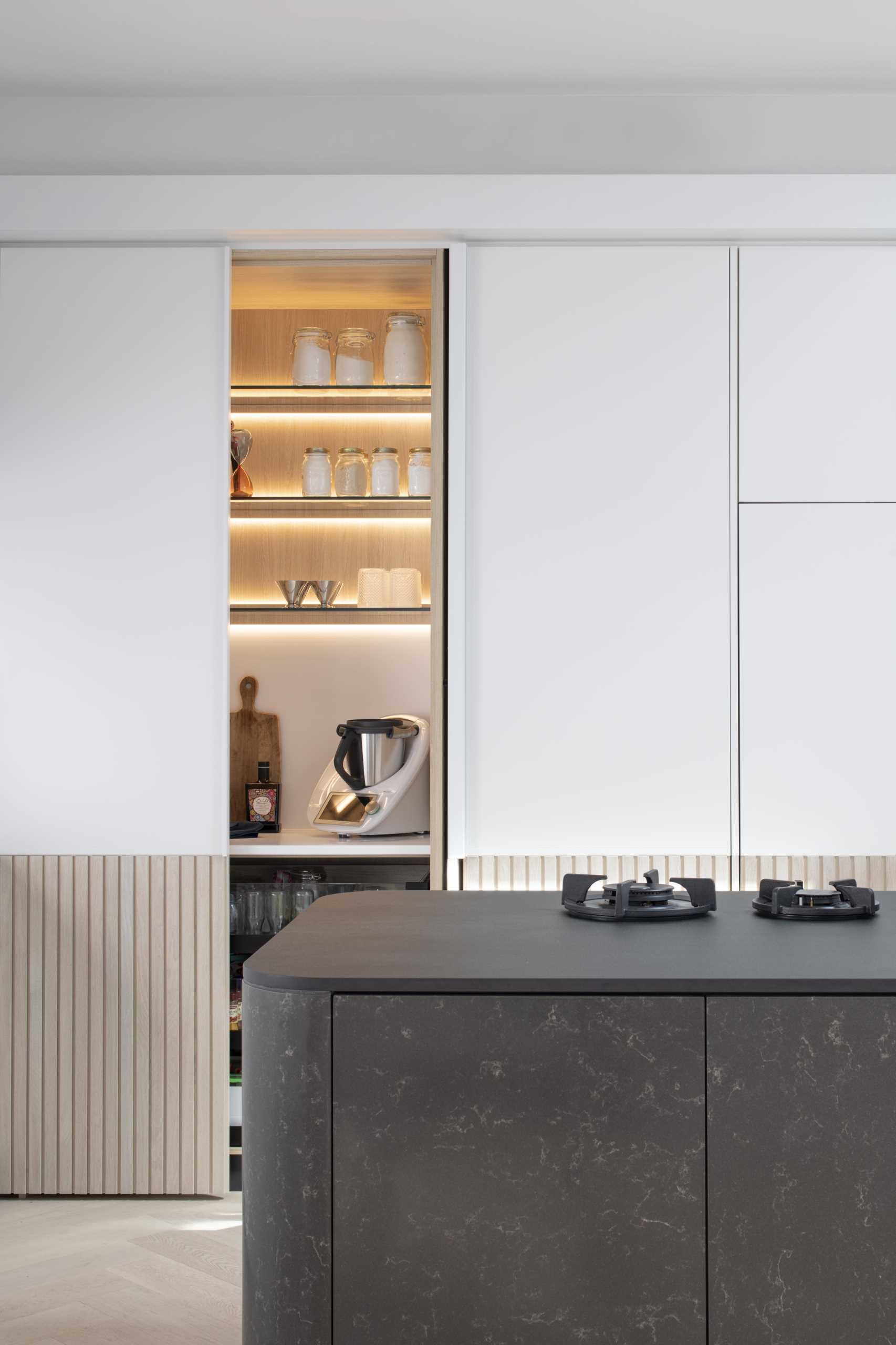 A modern white kitchen with wood paneling around the lower section of the cabinets. Integrated appliances have also been included in the kitchen design.