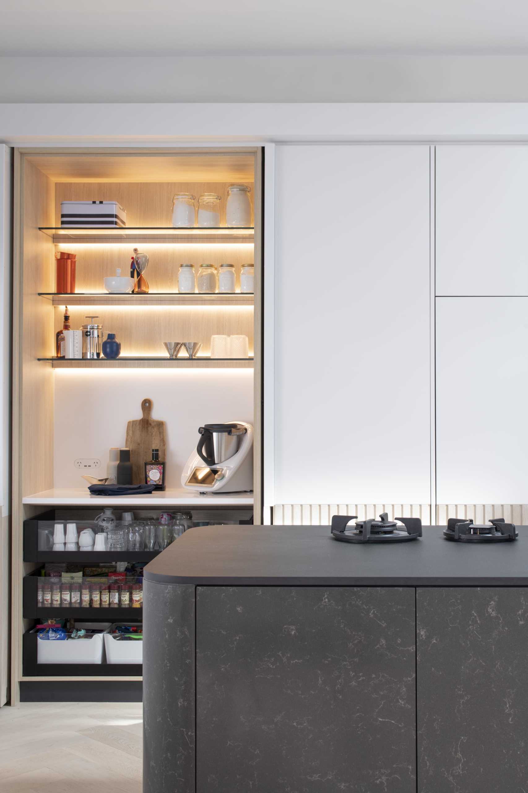 A modern white kitchen with wood paneling around the lower section of the cabinets. Integrated appliances have also been included in the kitchen design.