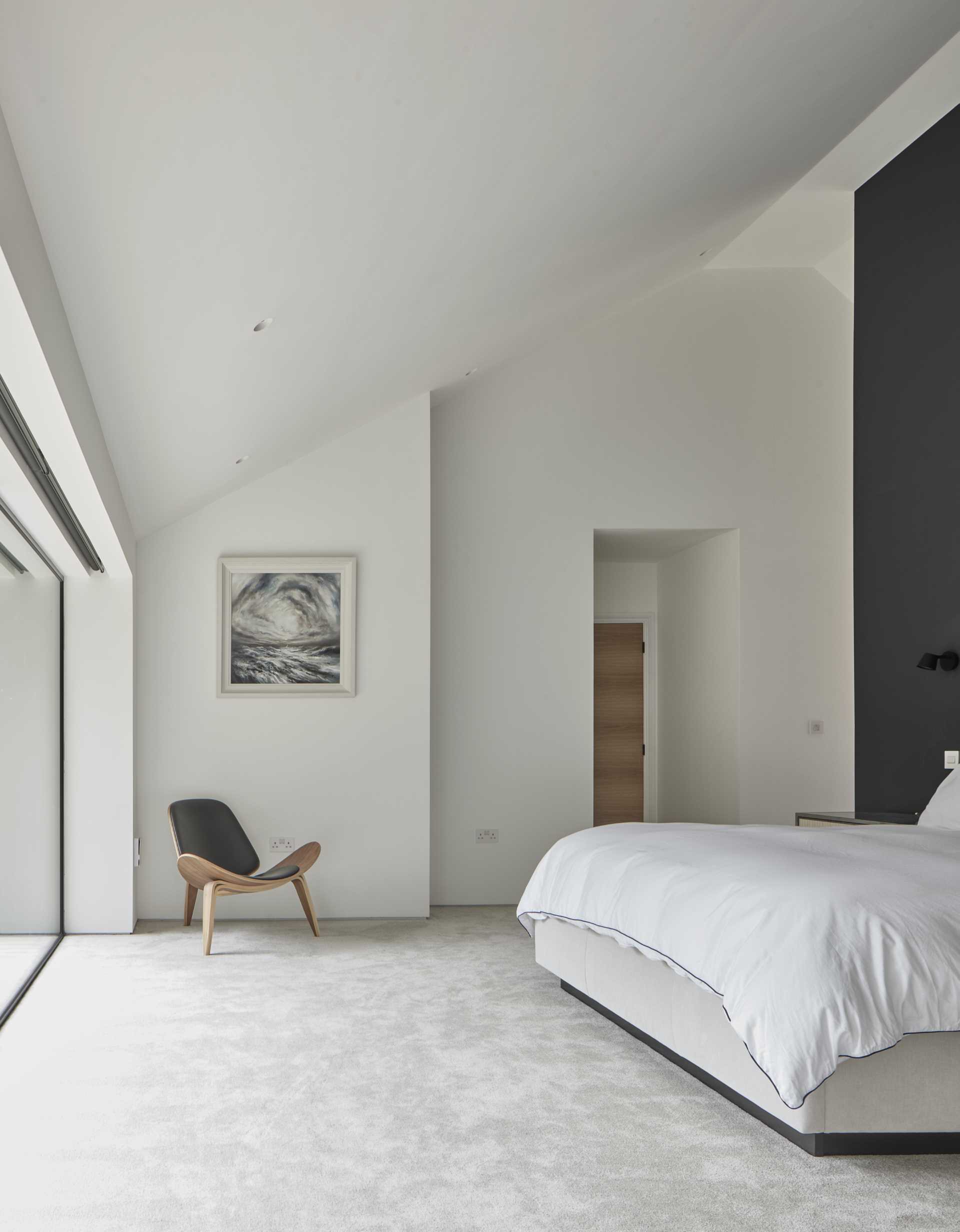 This primary bedroom that has large, cantilevered windows that project away from the home, creating a sensation of floating amidst the treetops.