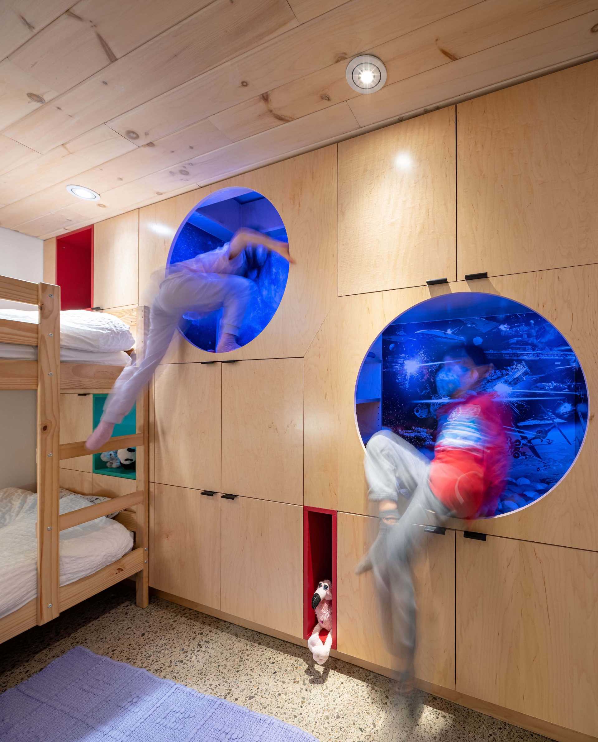 A kids bedroom with built-in storage in the form of cabinets and benches, as well as bunk beds, and two reading nooks.