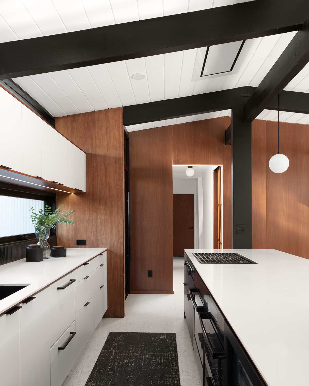 Wood, white, and black served as the clean palette for the new design of this  kitchen in a renovated mid-century modern home.