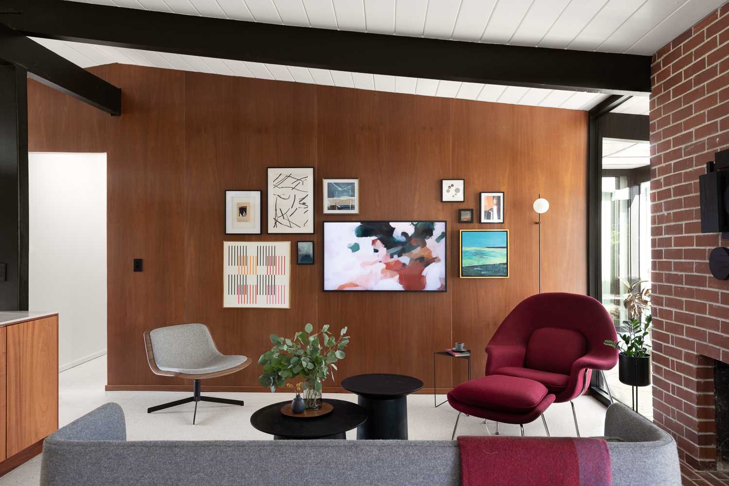 In the living room, the wood wall is accented by artwork, while a pop of colour has with furniture choices.