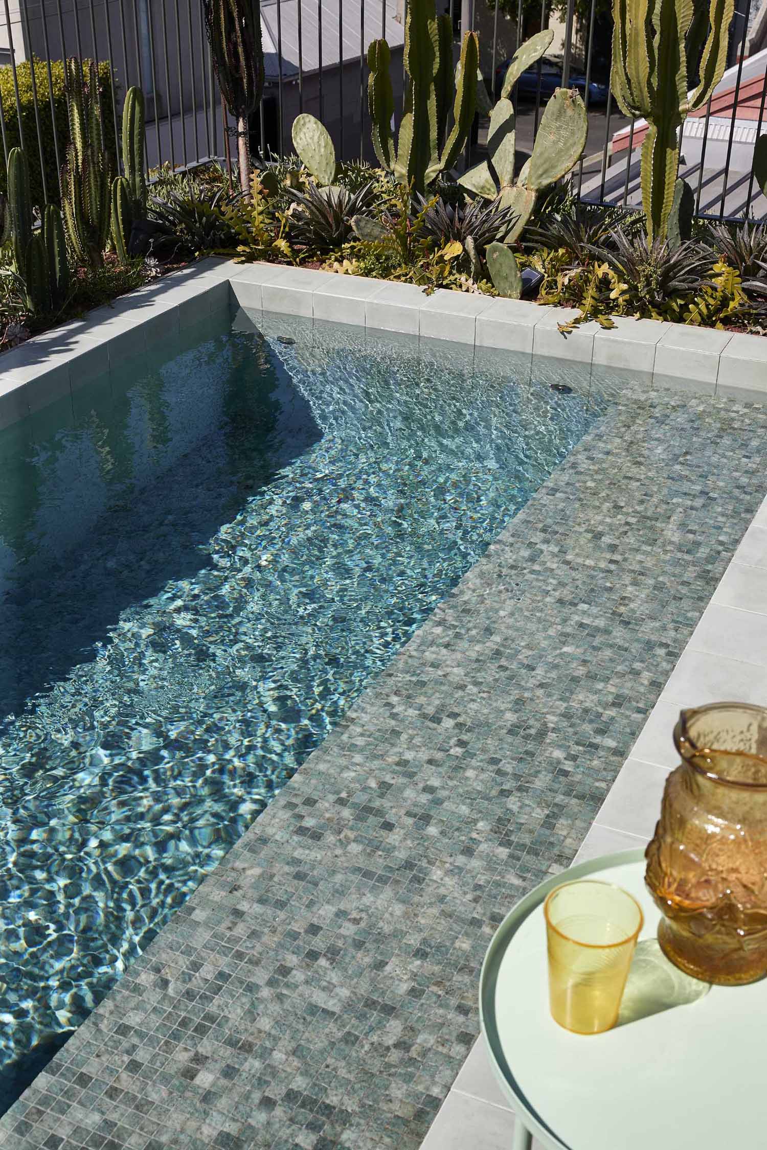 A rooftop terrace lined with steel-topped planter boxes, also includes a small pool and outdoor shower.