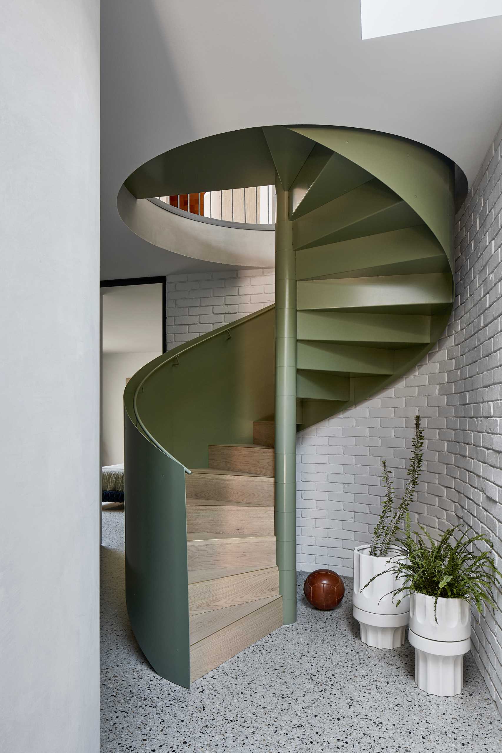 A green spiral staircase travels from the entry level to the main social areas of the home.