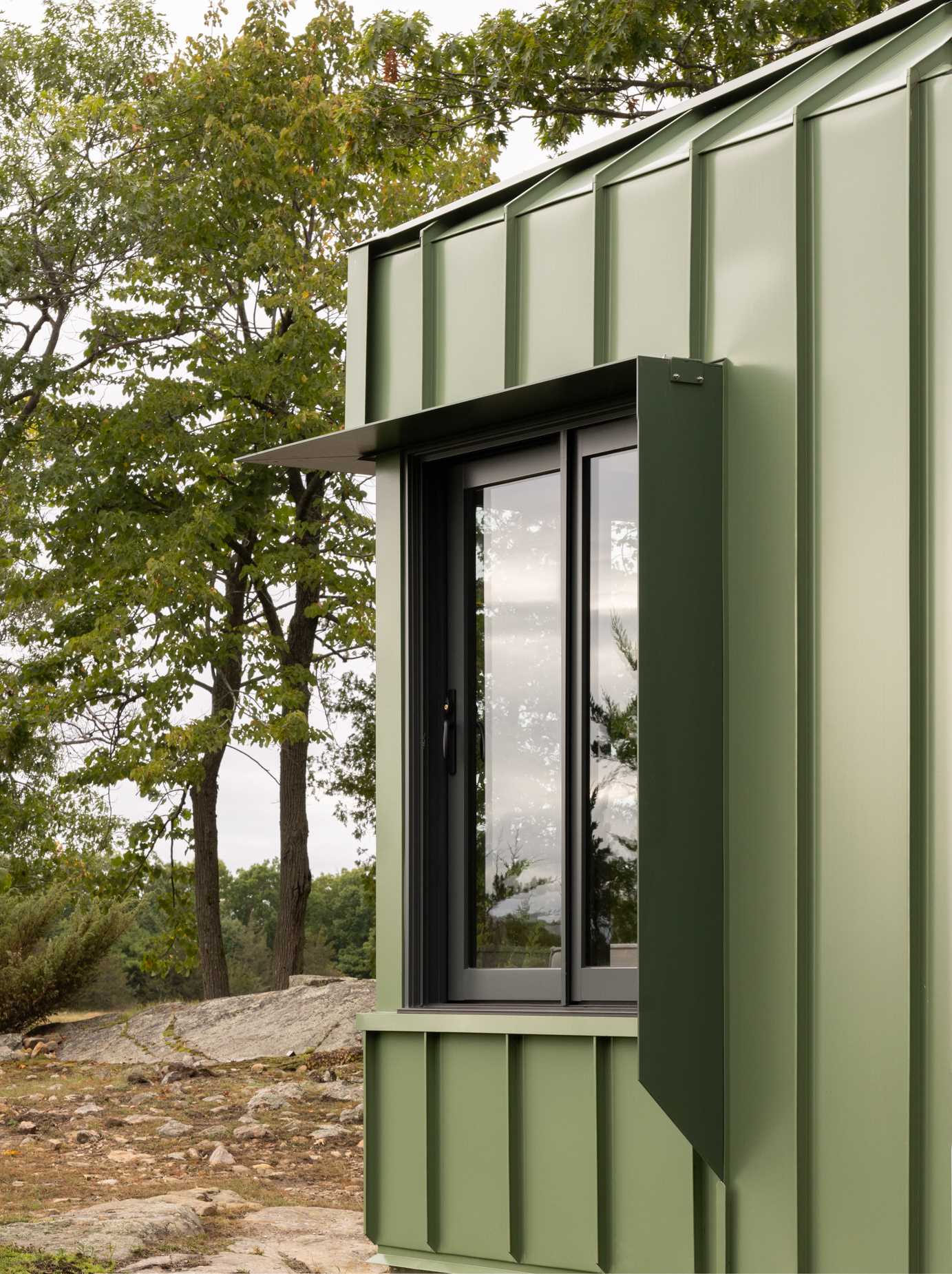 A modern cabin clad in sage green standing seam metal siding.