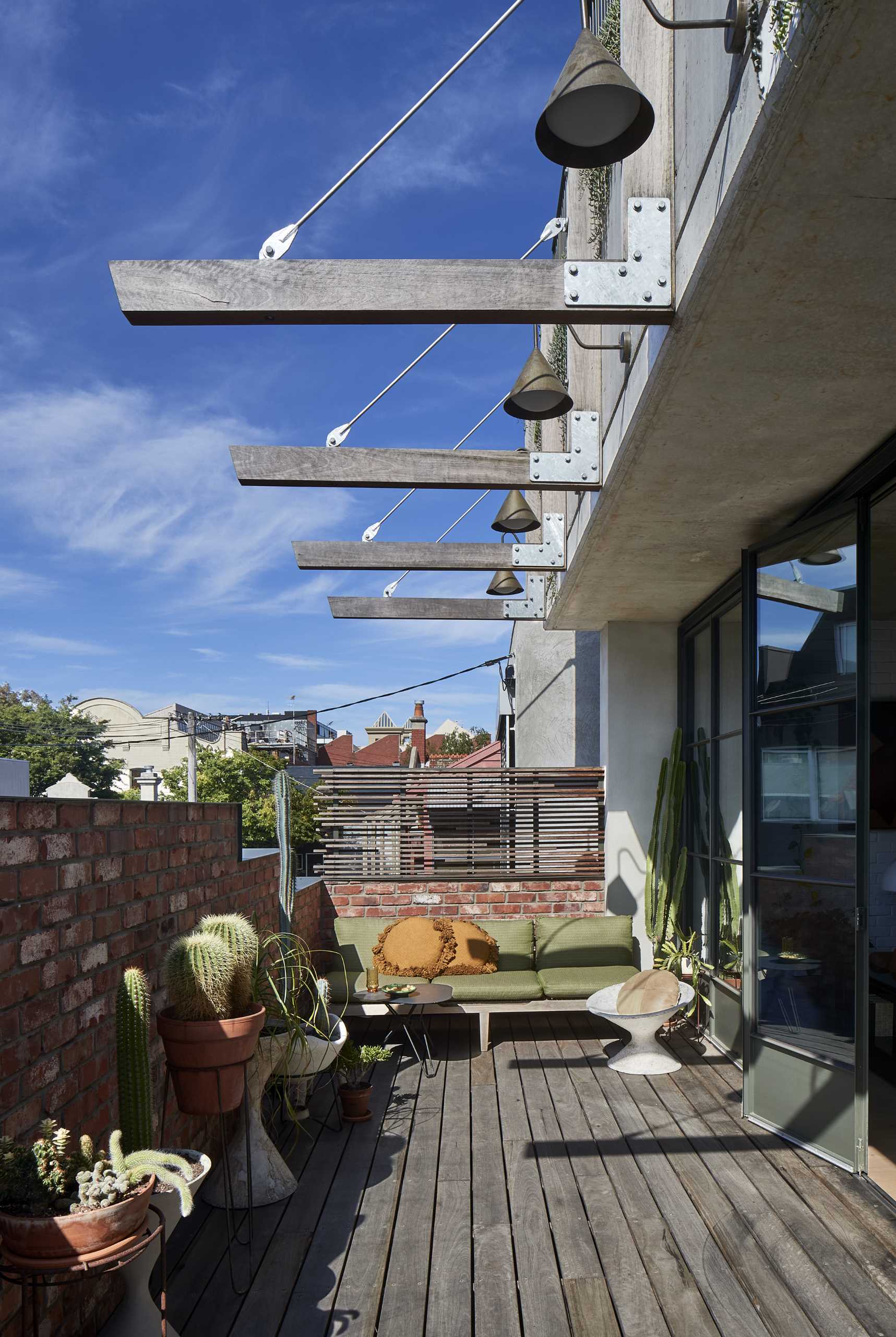 A folding steel and glass wall connects with the street-facing terrace tucked behind the stepped brick facade.