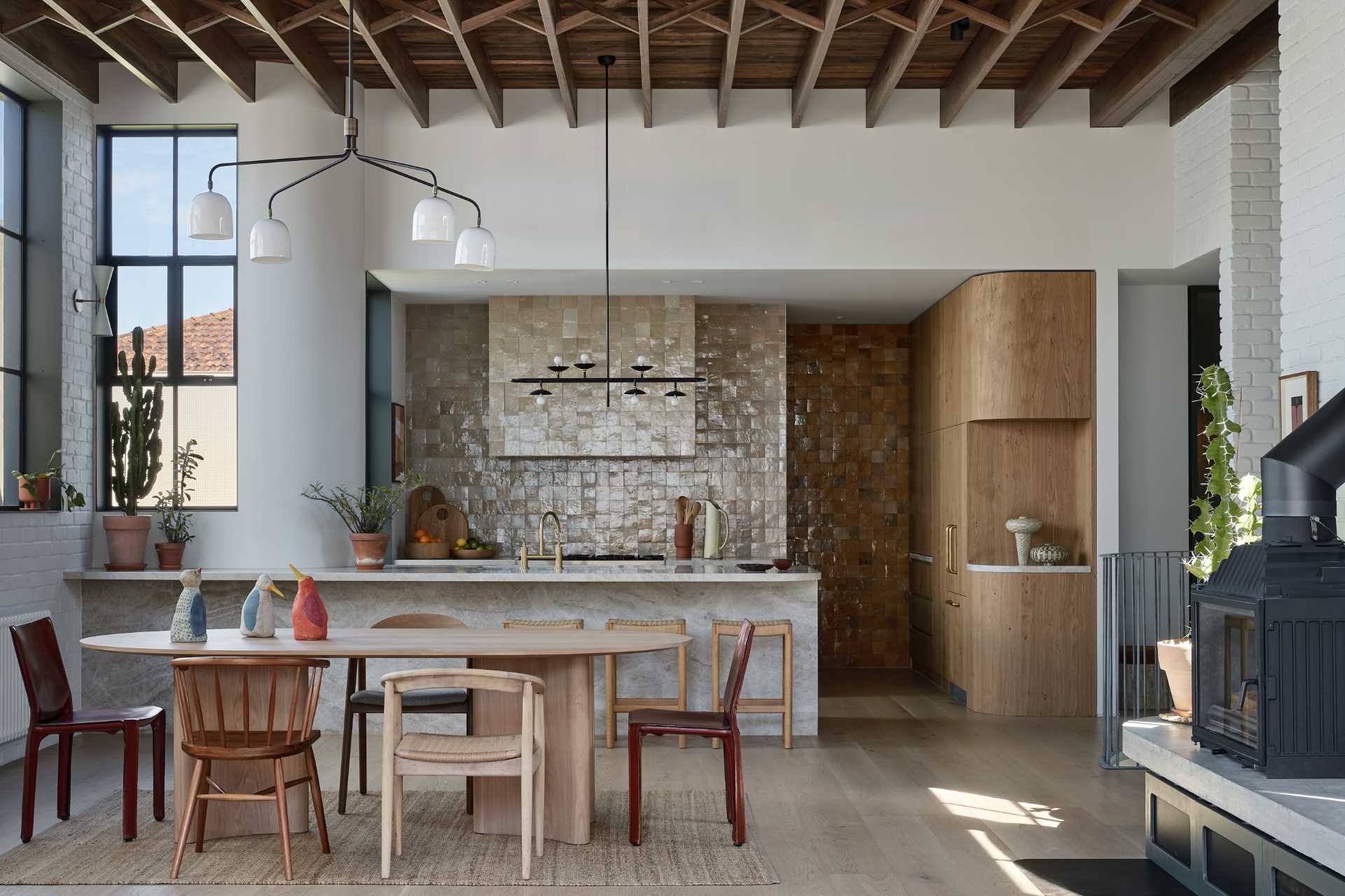 The kitchen is located at the end of the open-plan interior, with a tiled wall creating an eye-catching accent wall. Hidden from view is a pantry with additional storage and floating shelves.