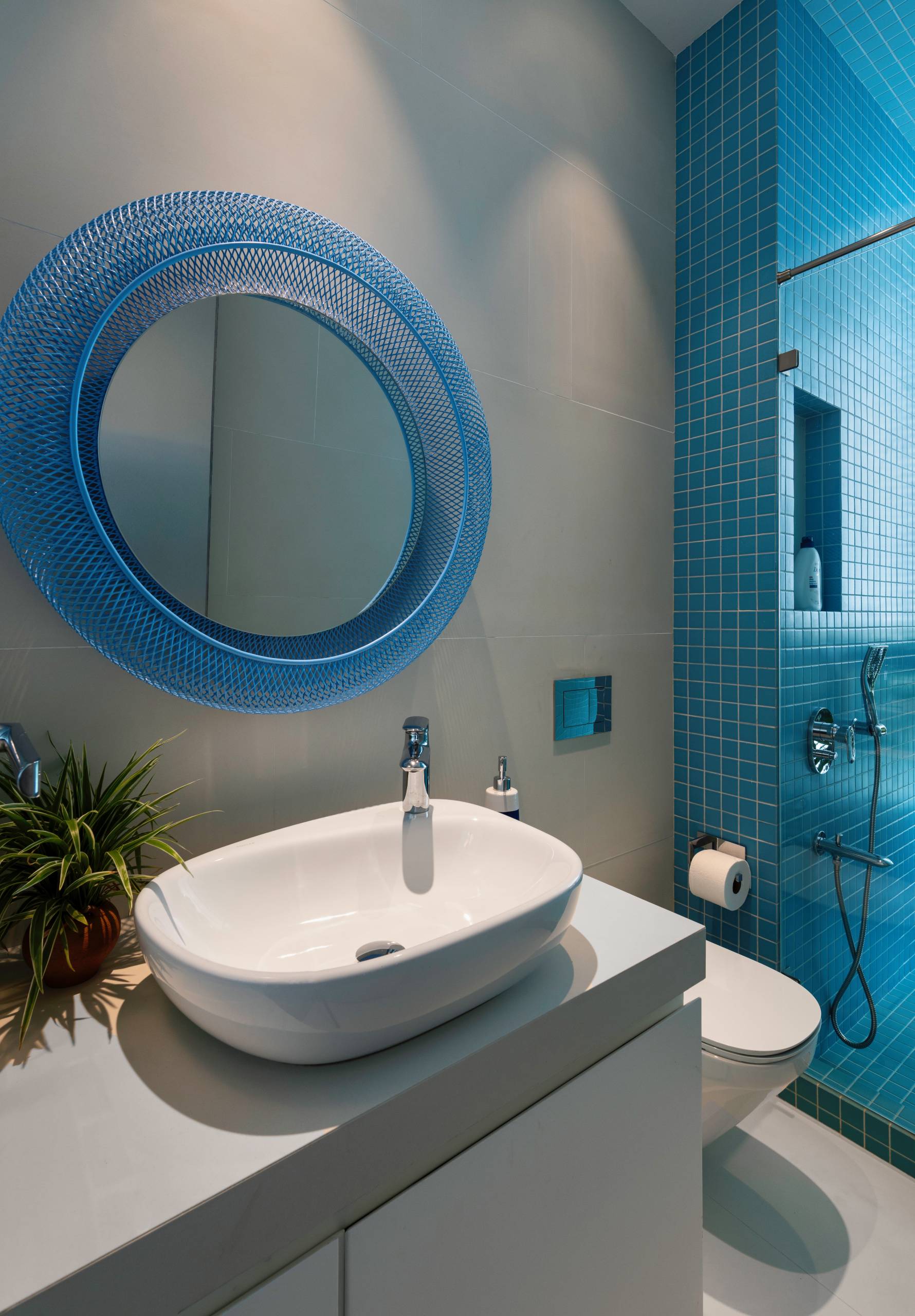 A modern bathroom with blue tiles and a blue mirror surround.