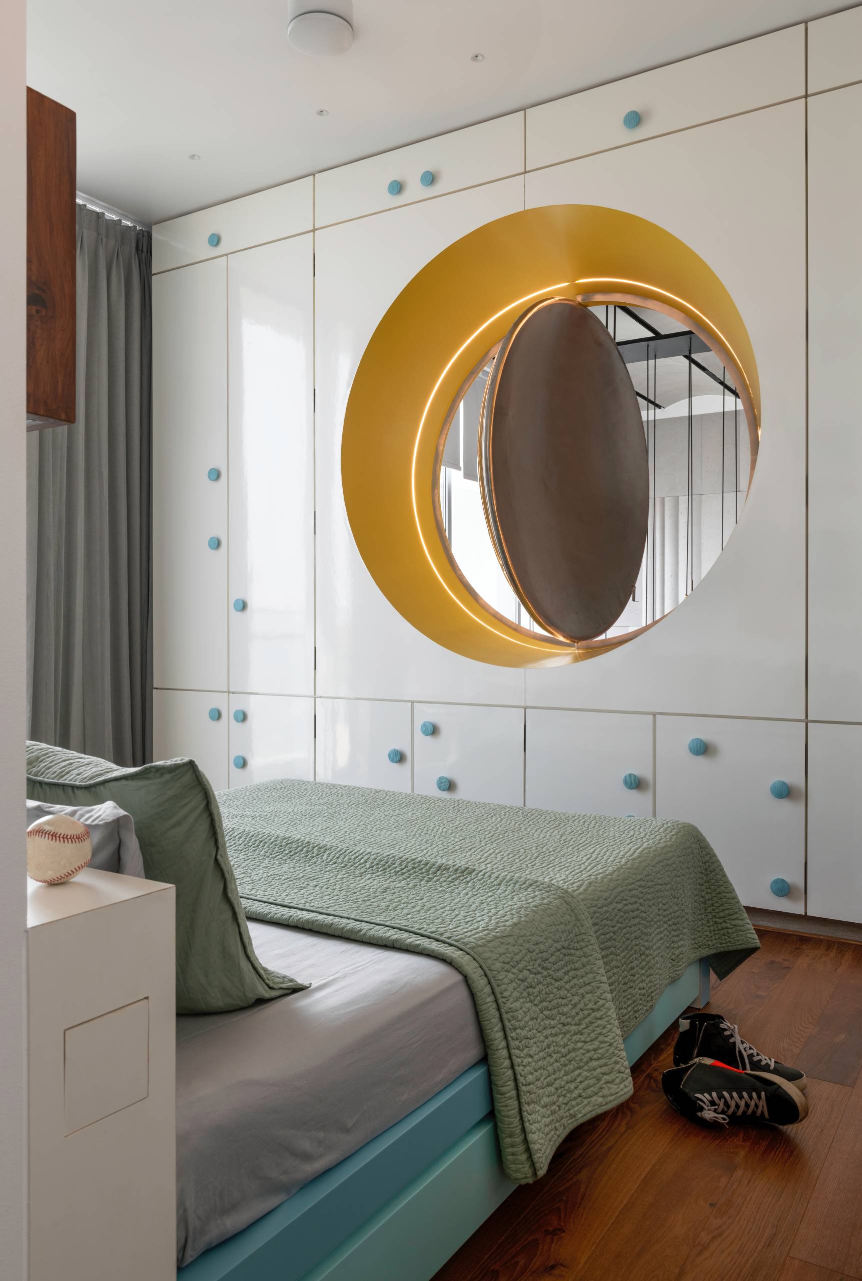 A modern bedroom with a circular opening that overlooks a double-height dining area.