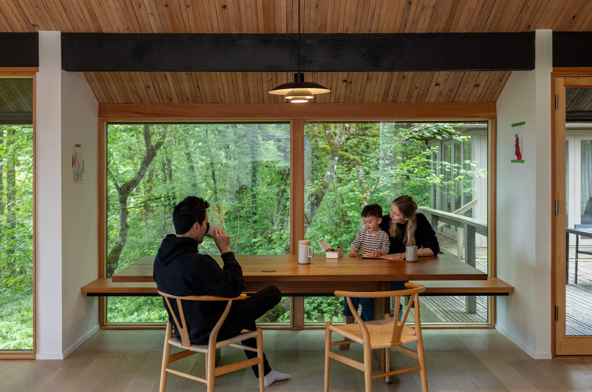 A dining nook featuring a custom fir bench is positioned in front of floor-to-ceiling glass. 