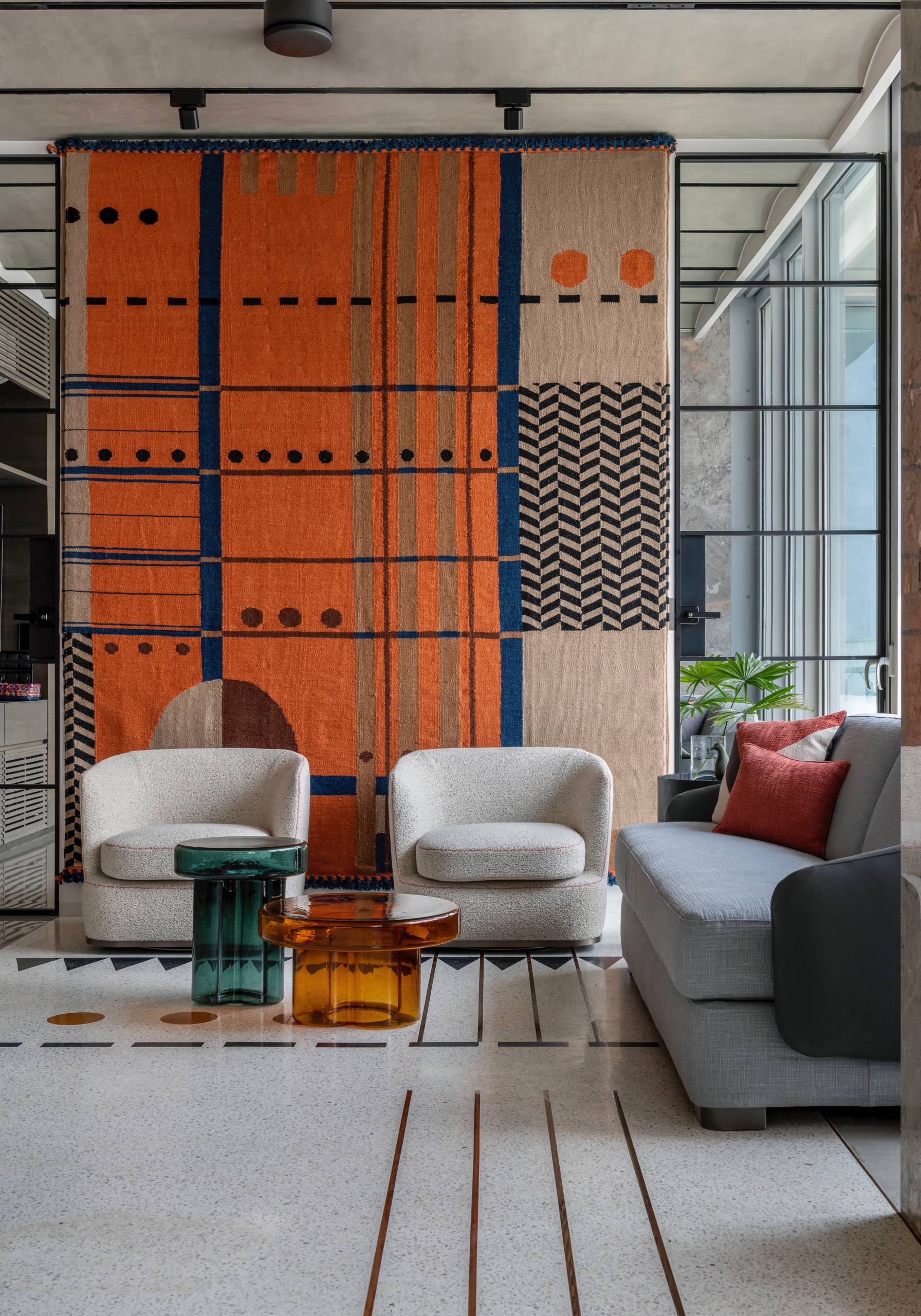 A modern living room in a penthouse, includes orange accents.