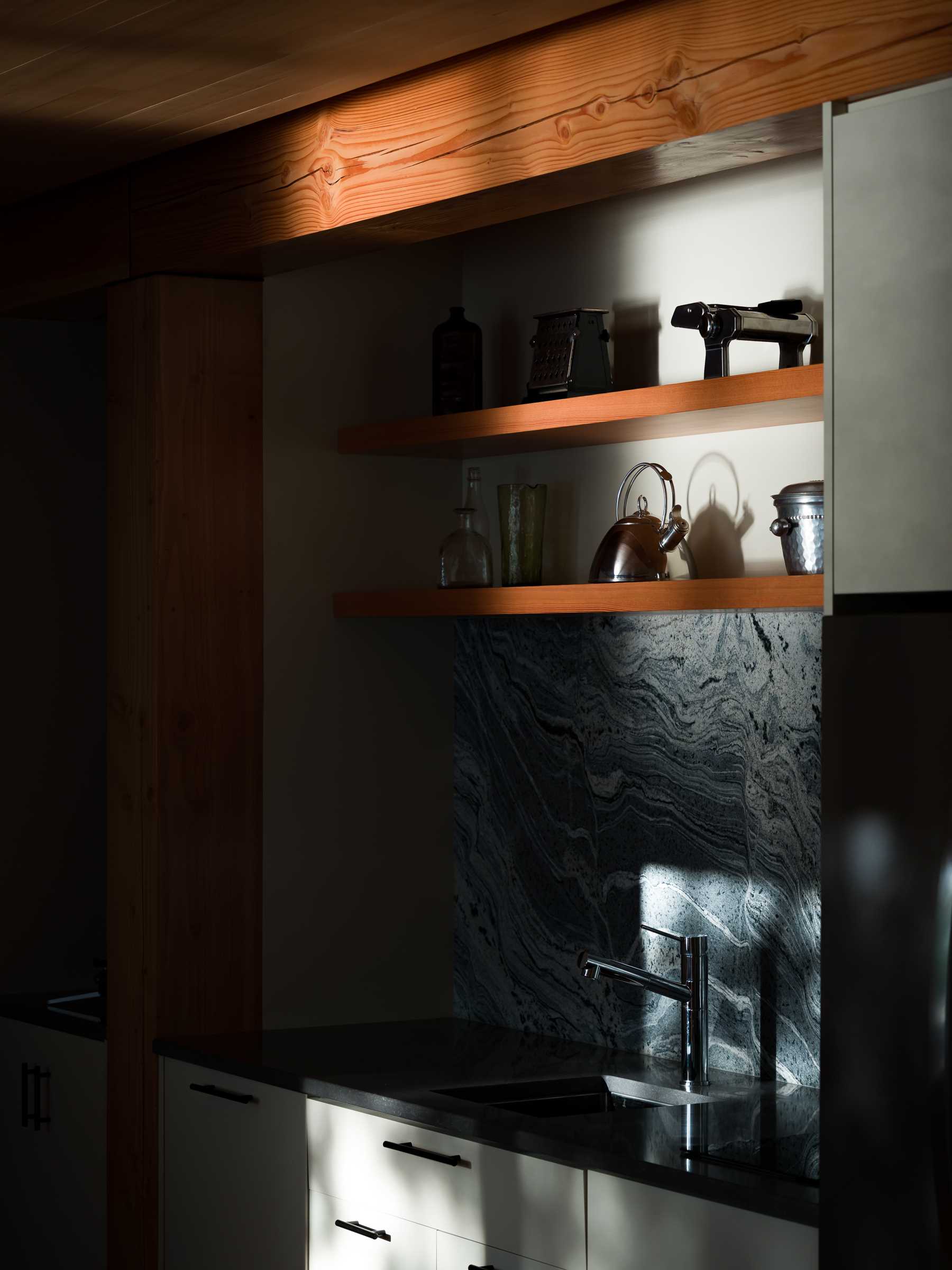 The dining area of this small cabin includes a wood bench that runs underneath the window, while the kitchen takes up the opposite wall.