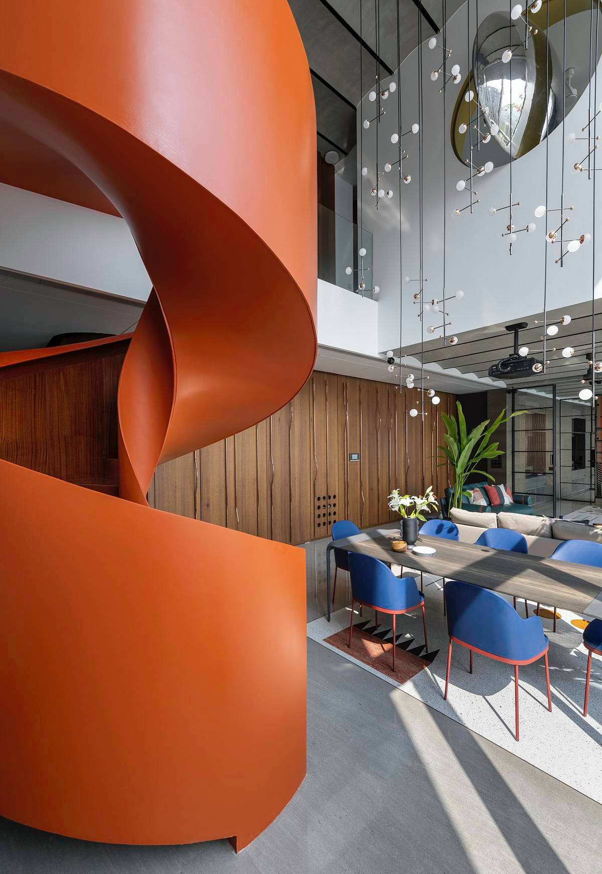 A modern penthouse with a bright orange spiral staircase.