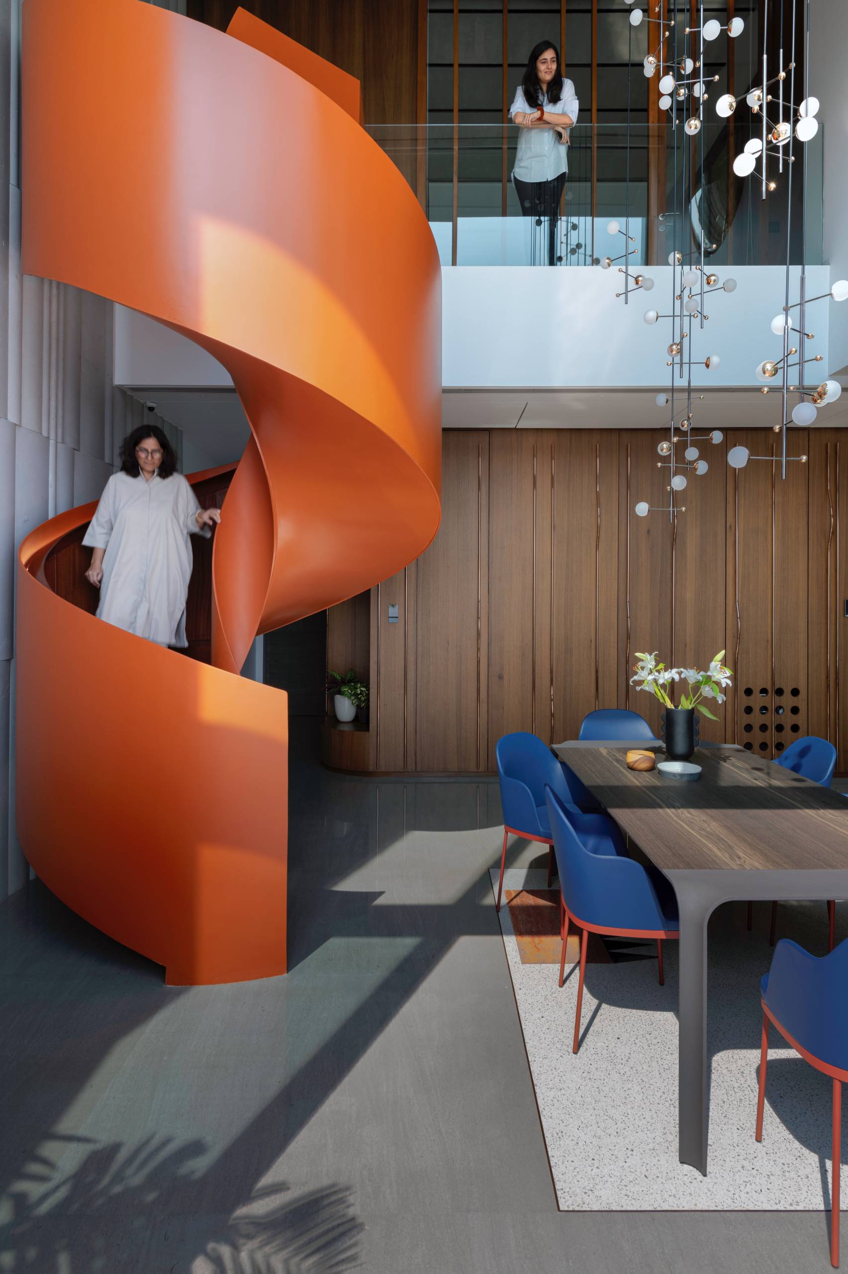 A modern penthouse with a bright orange spiral staircase.