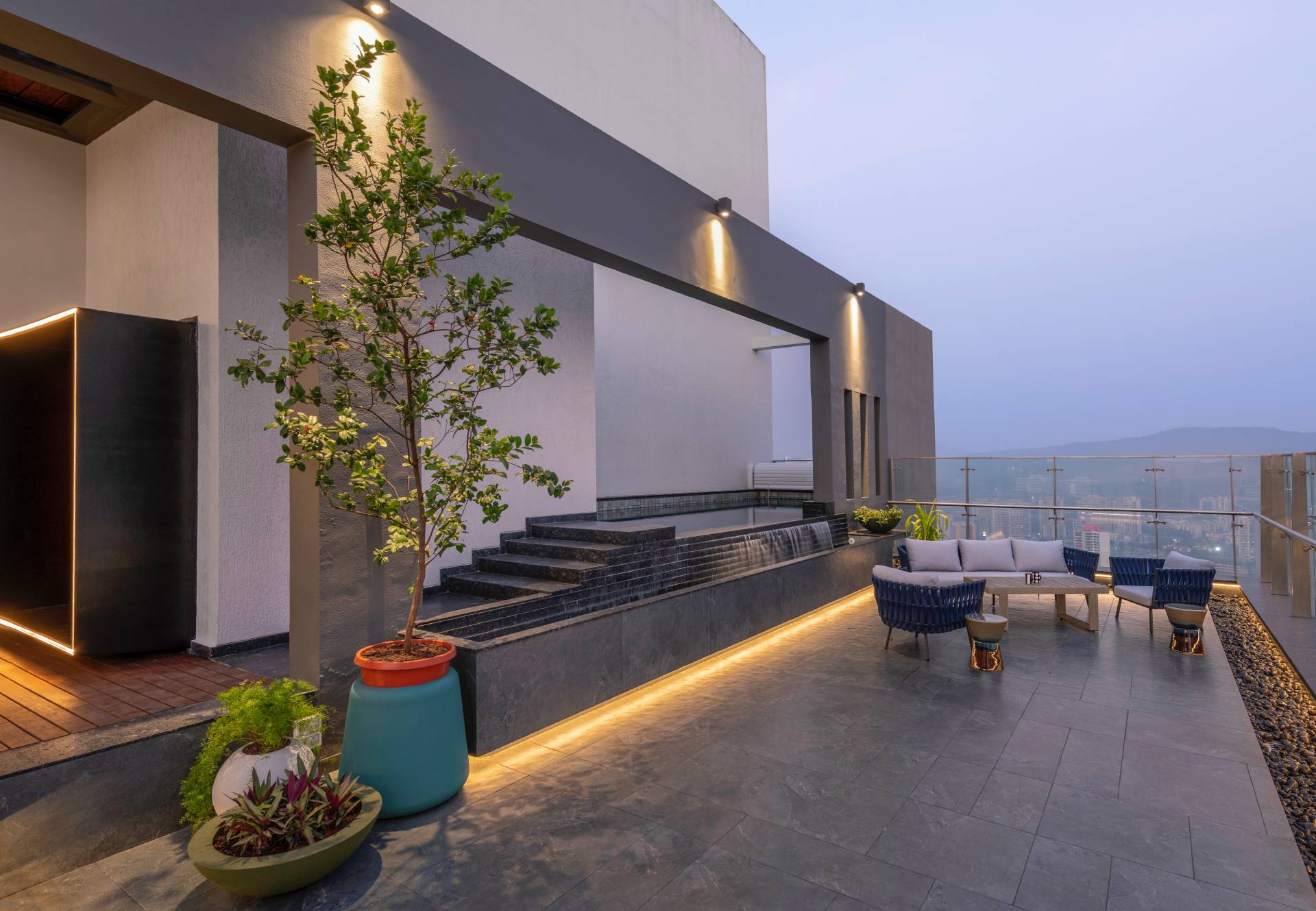 A modern penthouse with a terrace that has a dining area and multiple seating areas.