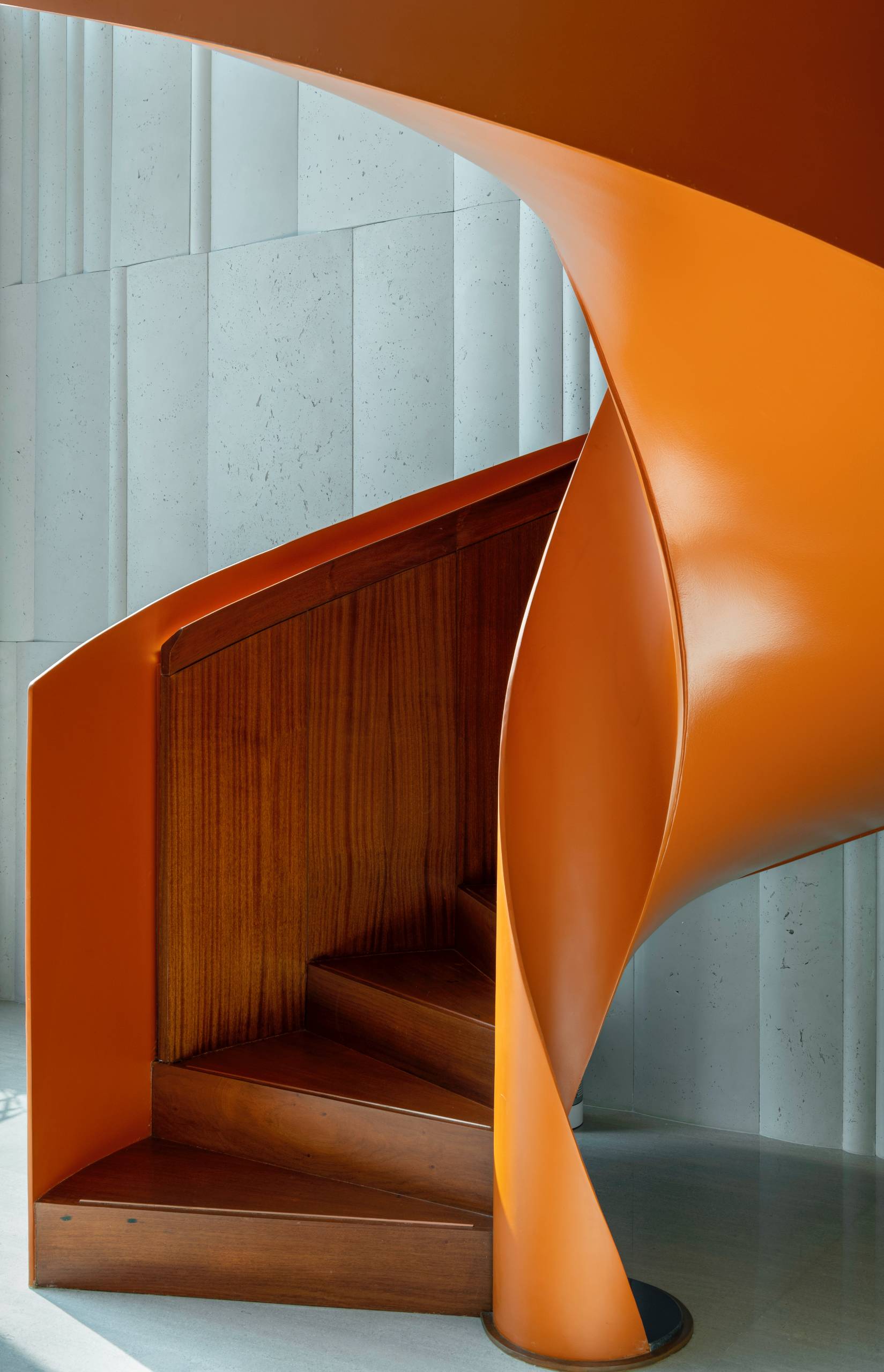 A modern penthouse with a bright orange spiral staircase.