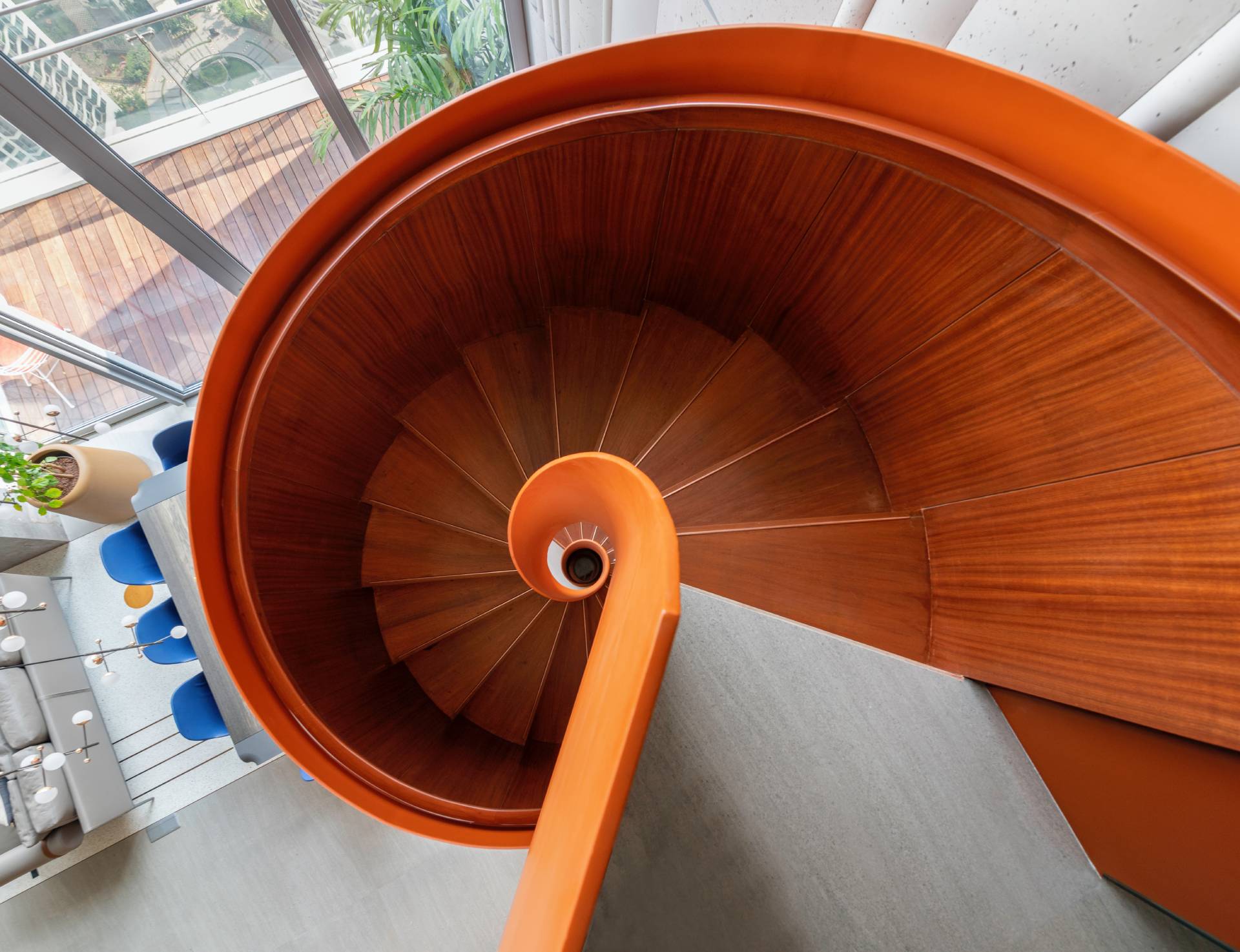 A modern penthouse with a bright orange spiral staircase.