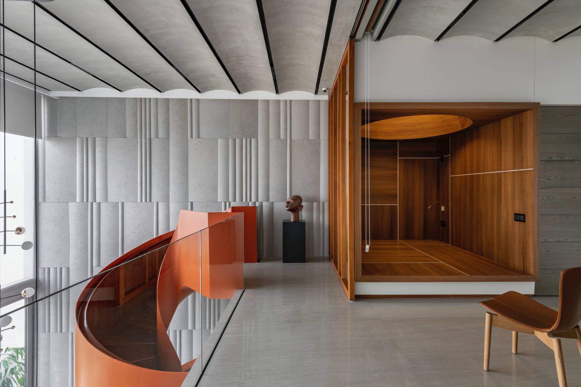 A modern penthouse with a bright orange spiral staircase.