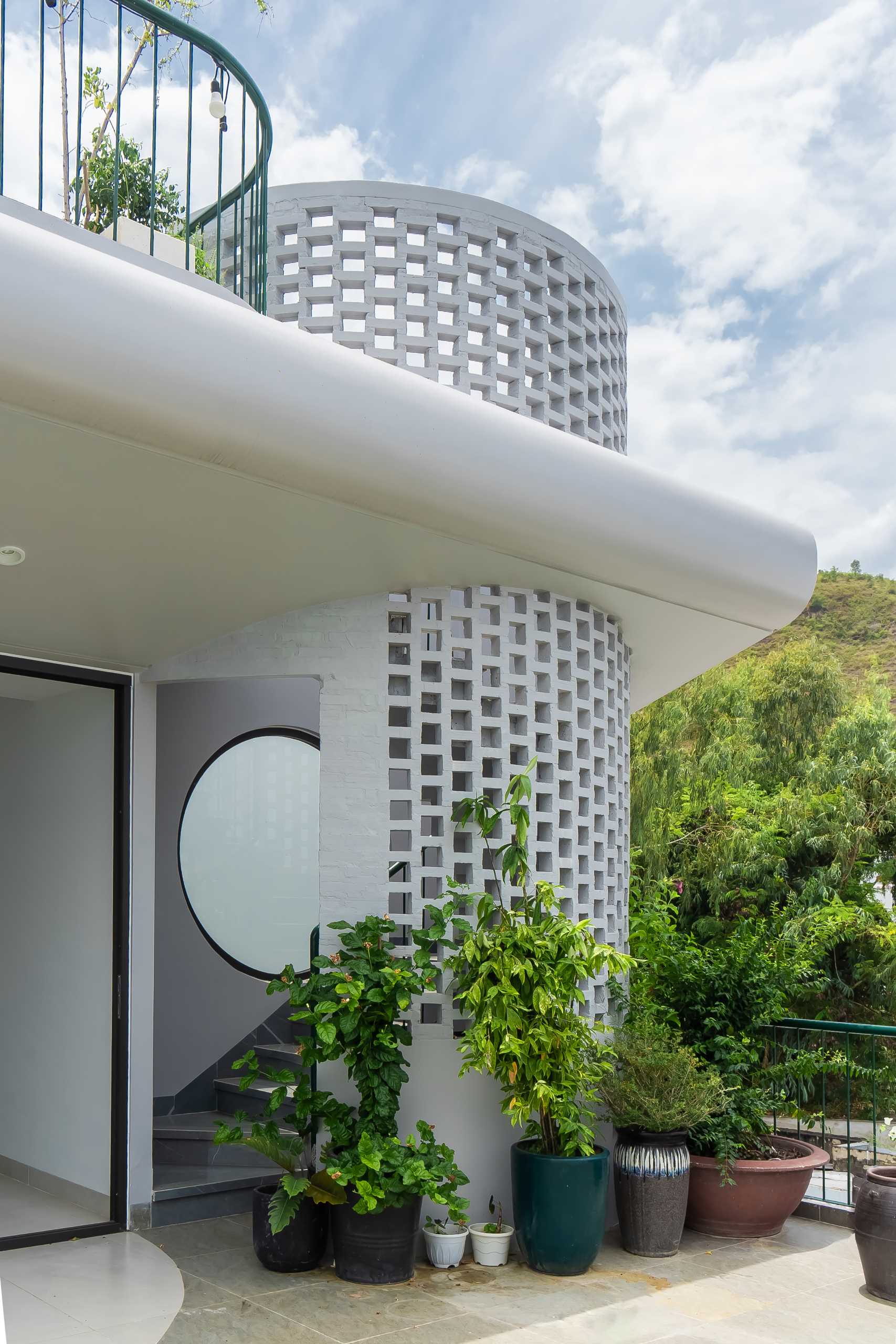 Spiral stairs lead to the rooftop of this villa where a gathering space can be found.