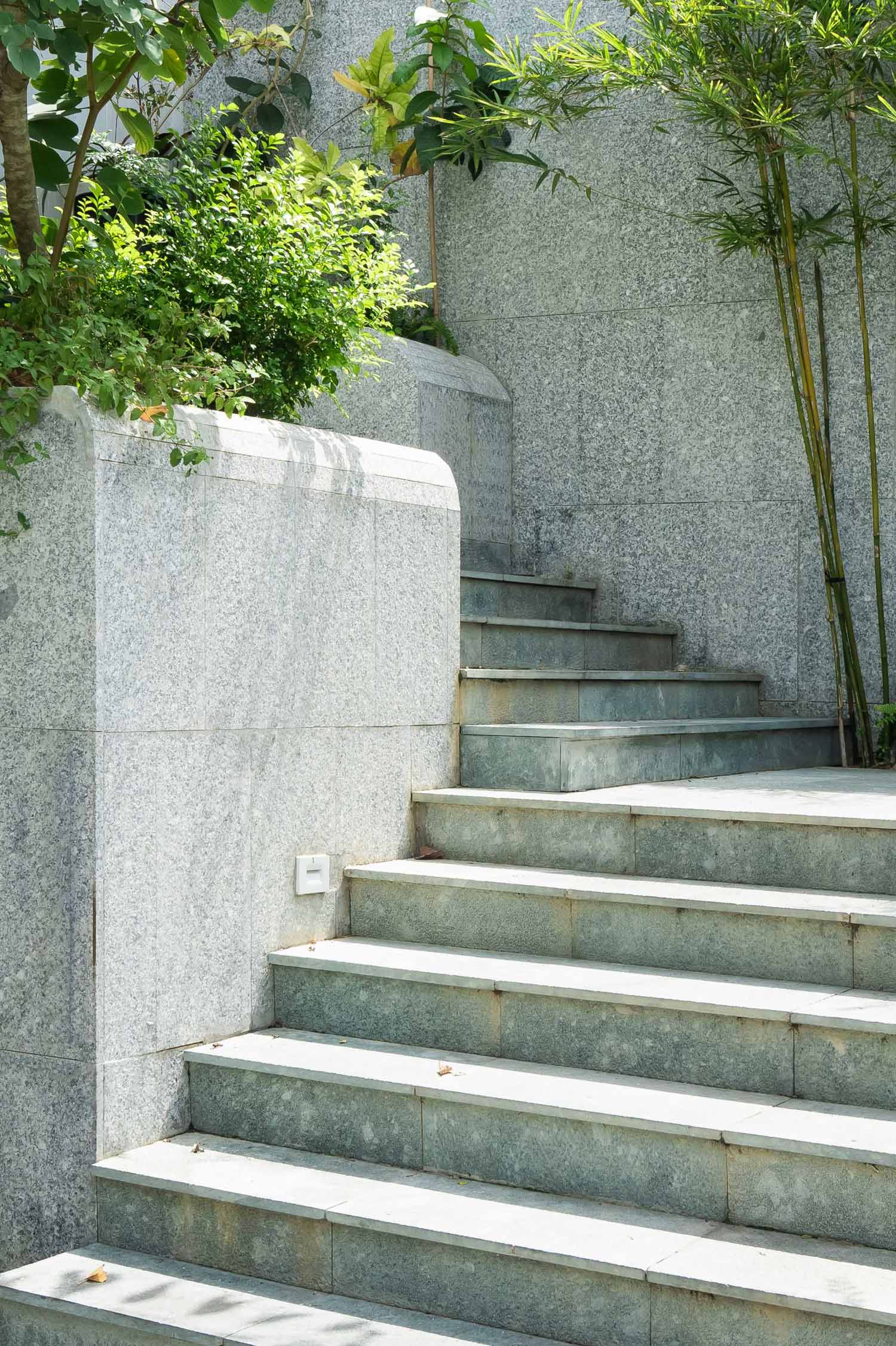 The front courtyard is designed with a series of long cascading steps resembling a waterfall, where carefully tended greenery and flowers weave into the house.