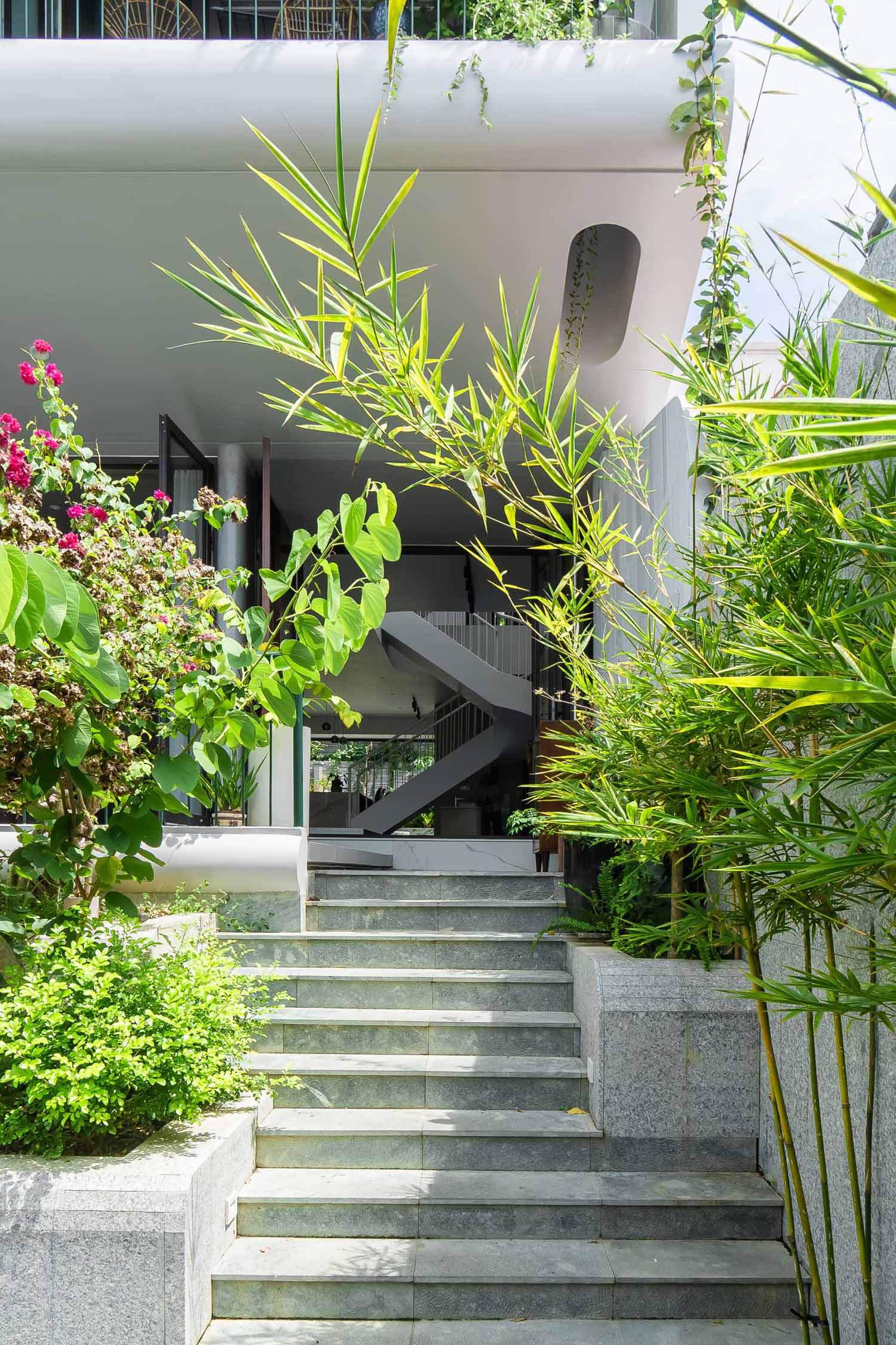 The front courtyard is designed with a series of long cascading steps resembling a waterfall, where carefully tended greenery and flowers weave into the house.