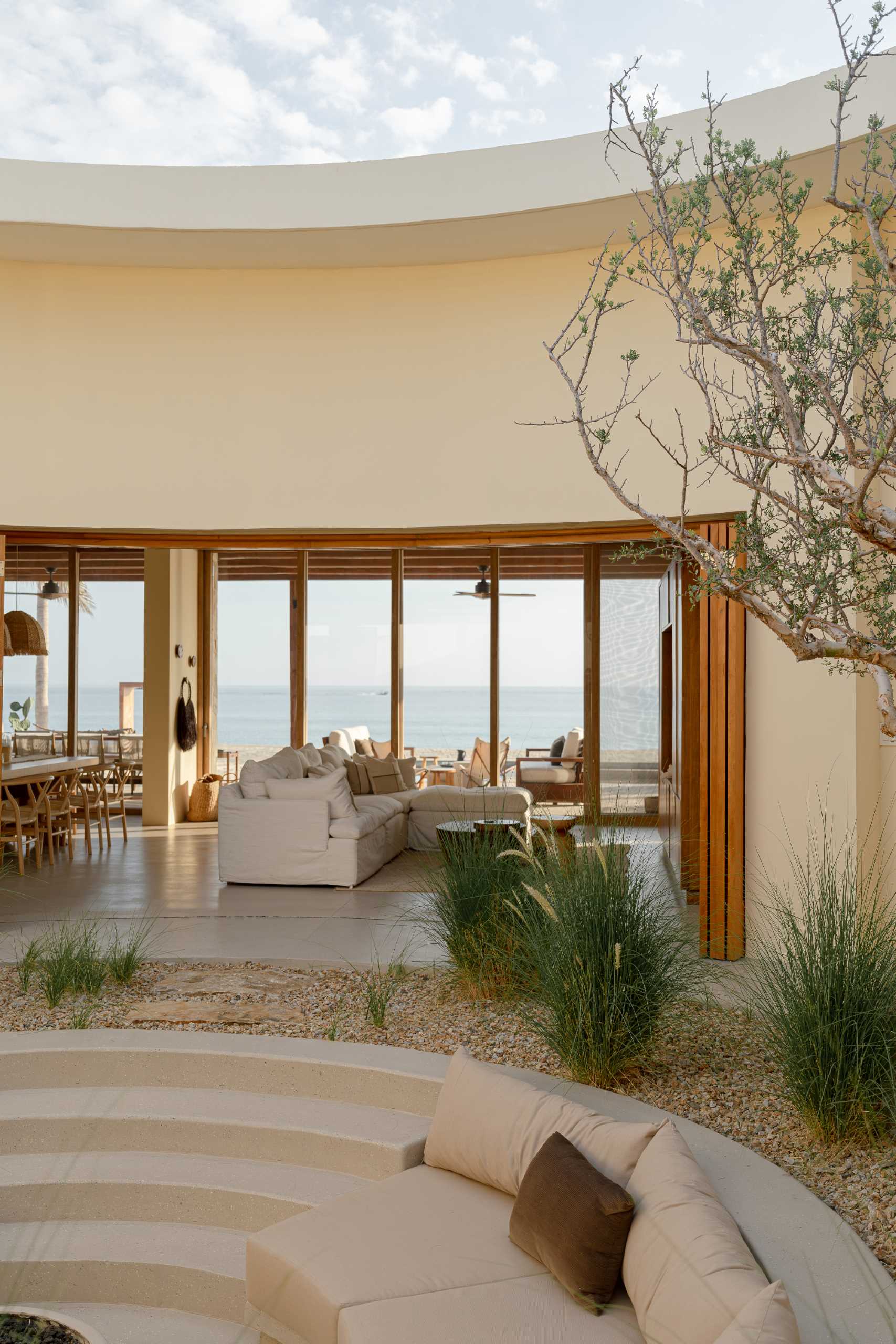 Surrounding the central patio of this contemporary house, the living spaces open fully from the entrance to the beach terrace, allowing for cross-ventilation and seamless integration between spaces.