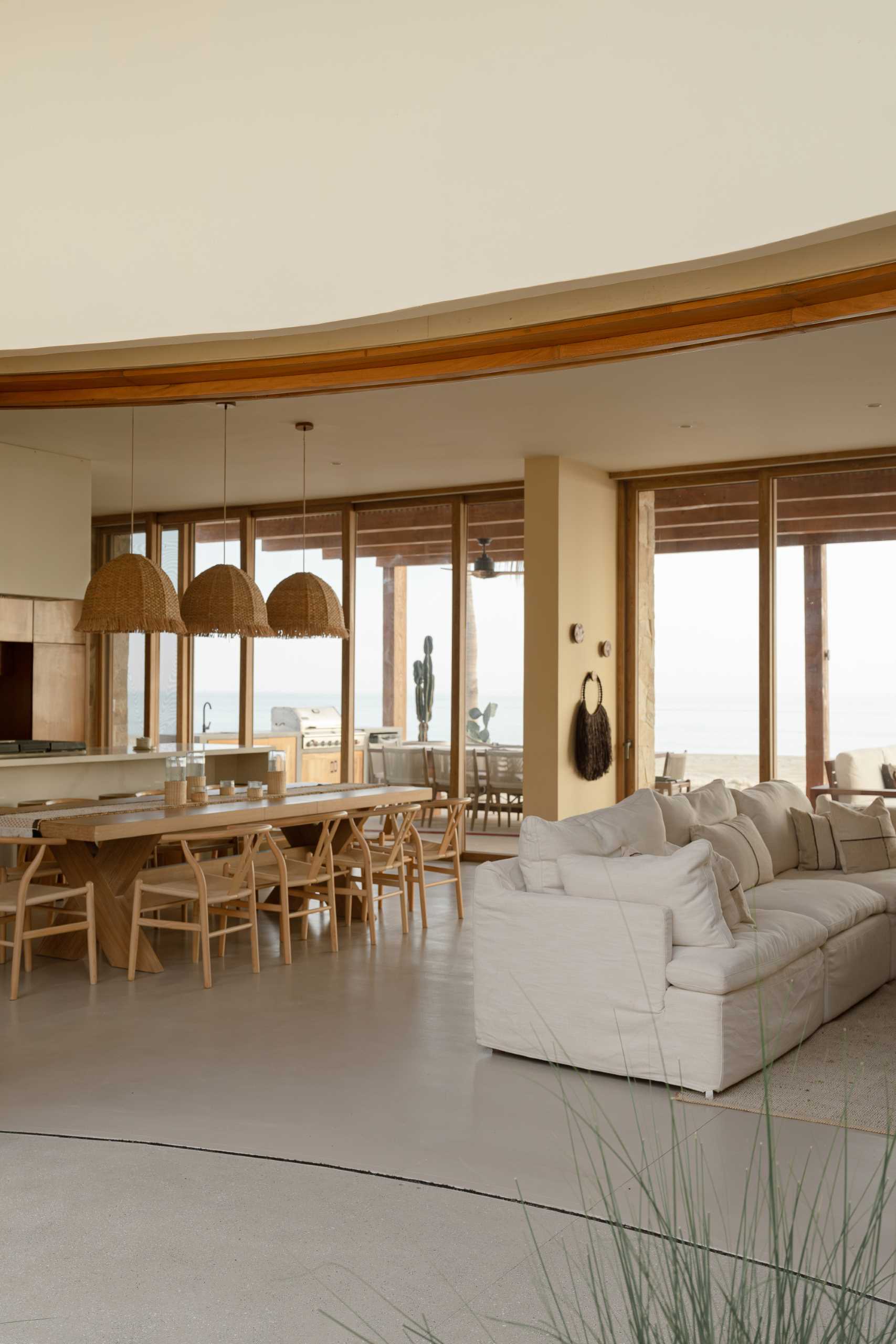 This contemporary beachouse has a open-plan living room, dining area, and kitchen with a calm interior palette.