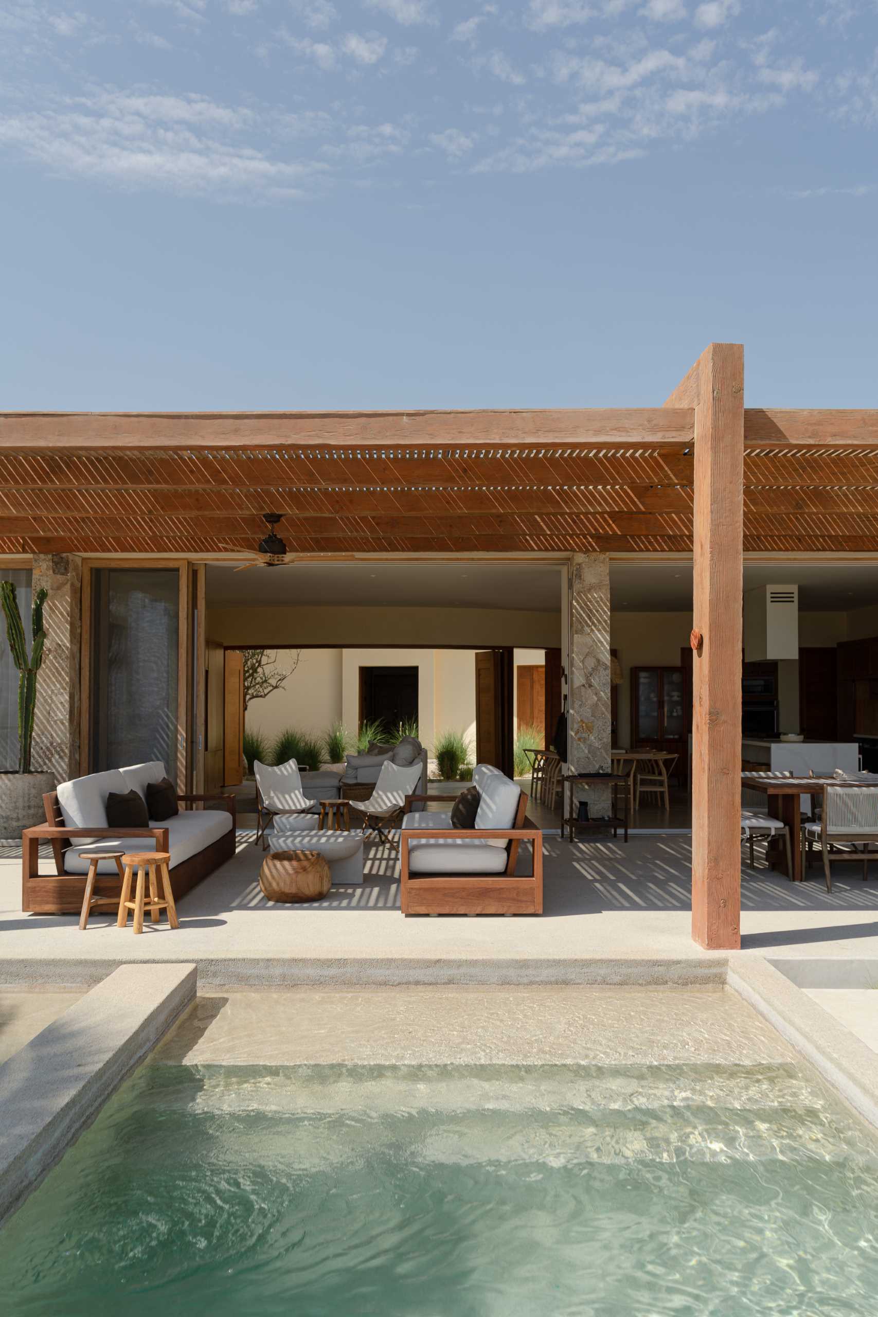 A contemporary stone home includes a spacious terrace, as well as a series of sculptural concrete cubes that form the pool and jacuzzi, while steps lead directly to the sand.