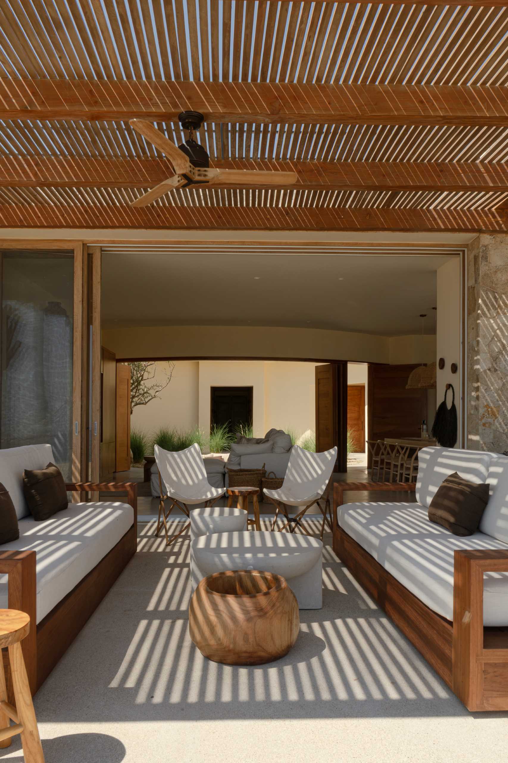 A contemporary stone home includes a spacious terrace, as well as a series of sculptural concrete cubes that form the pool and jacuzzi, while steps lead directly to the sand.