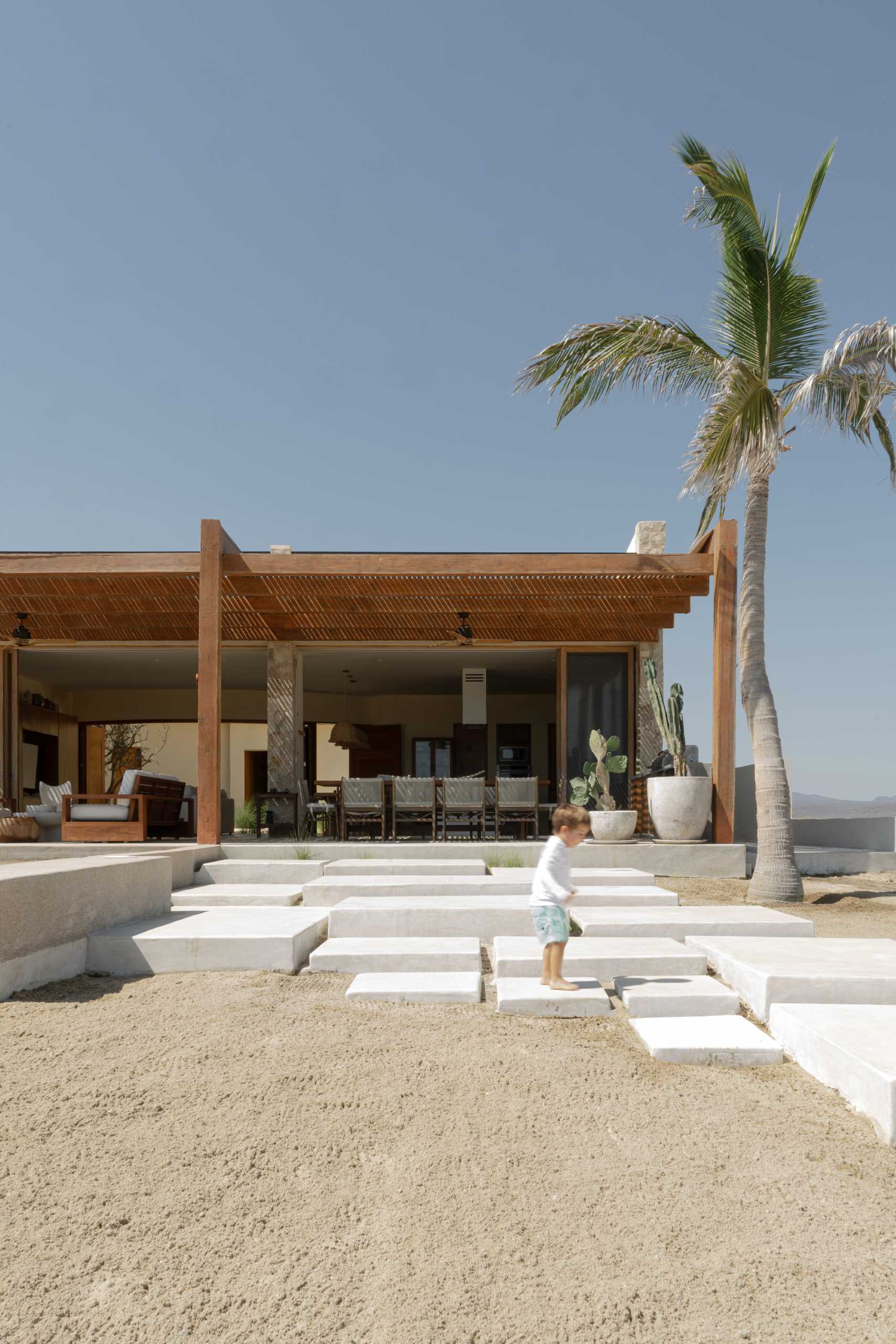 A contemporary stone home includes a spacious terrace, as well as a series of sculptural concrete cubes that form the pool and jacuzzi, while steps lead directly to the sand.