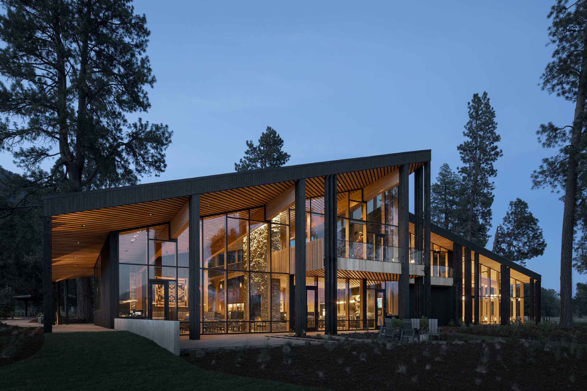 A modern ranch lodge with a black charred cedar exterior (shou sugi ban) and a warm wood interior.