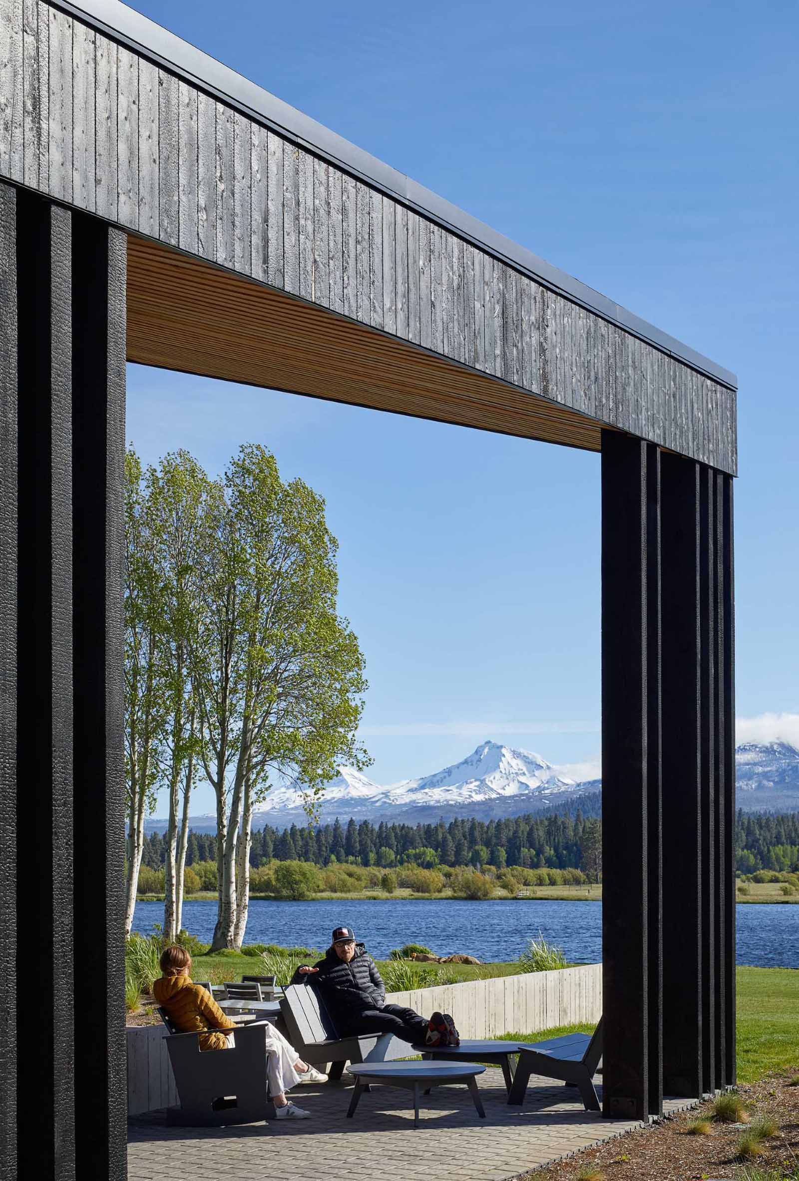 A modern ranch lodge with a black charred cedar exterior (shou sugi ban) and a warm wood interior.