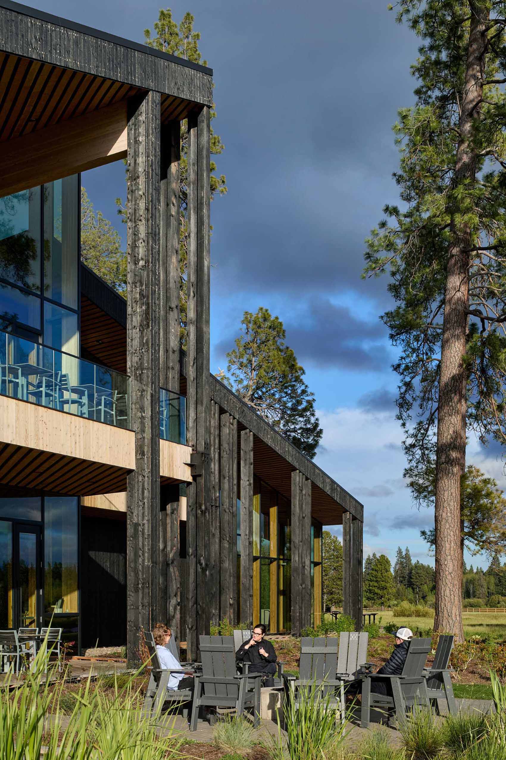 A modern ranch lodge with a black charred cedar exterior (shou sugi ban) and a warm wood interior.