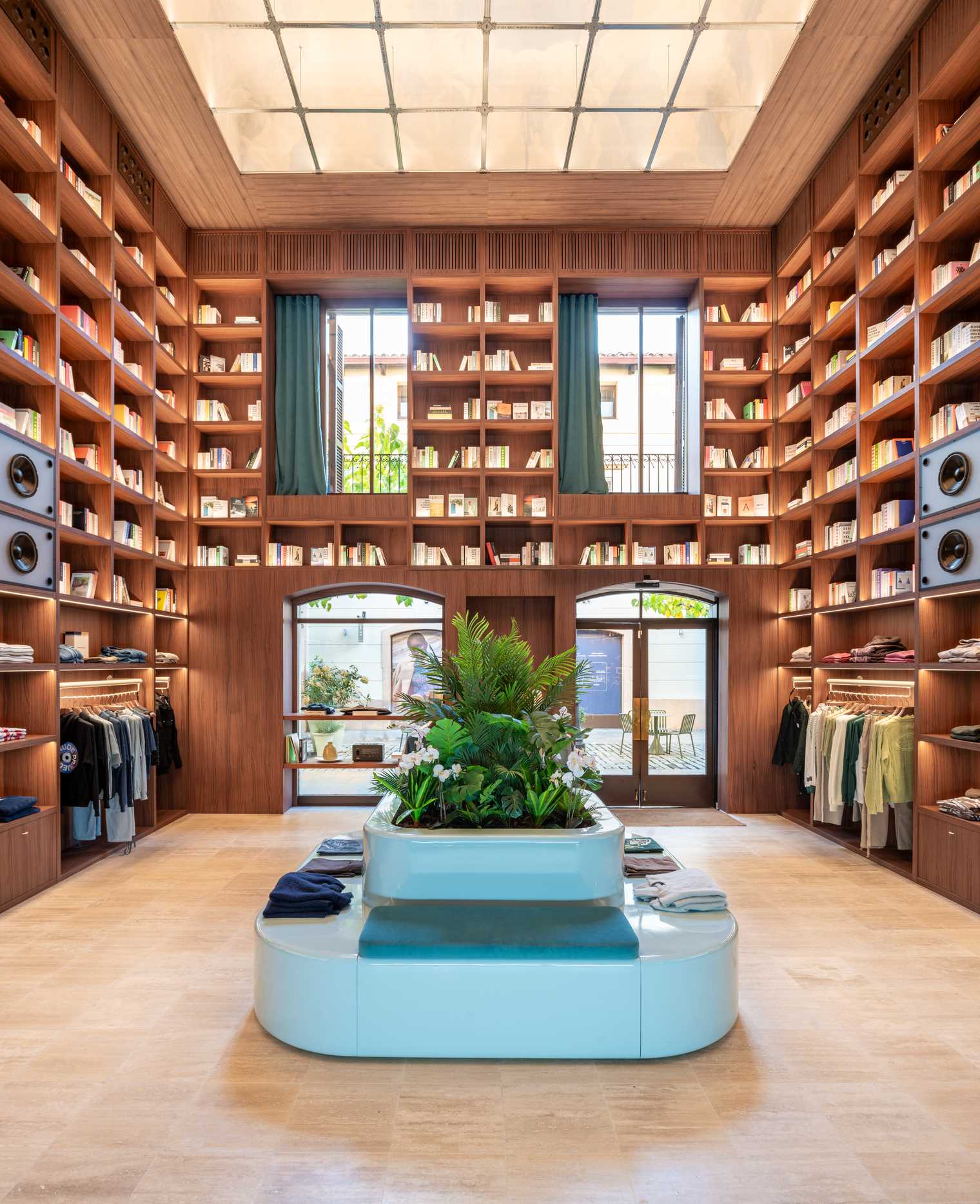 A modern streetwear retail store with 19-foot-high wooden bookshelves, a DJ booth, and a fitting room with baby blue accents.