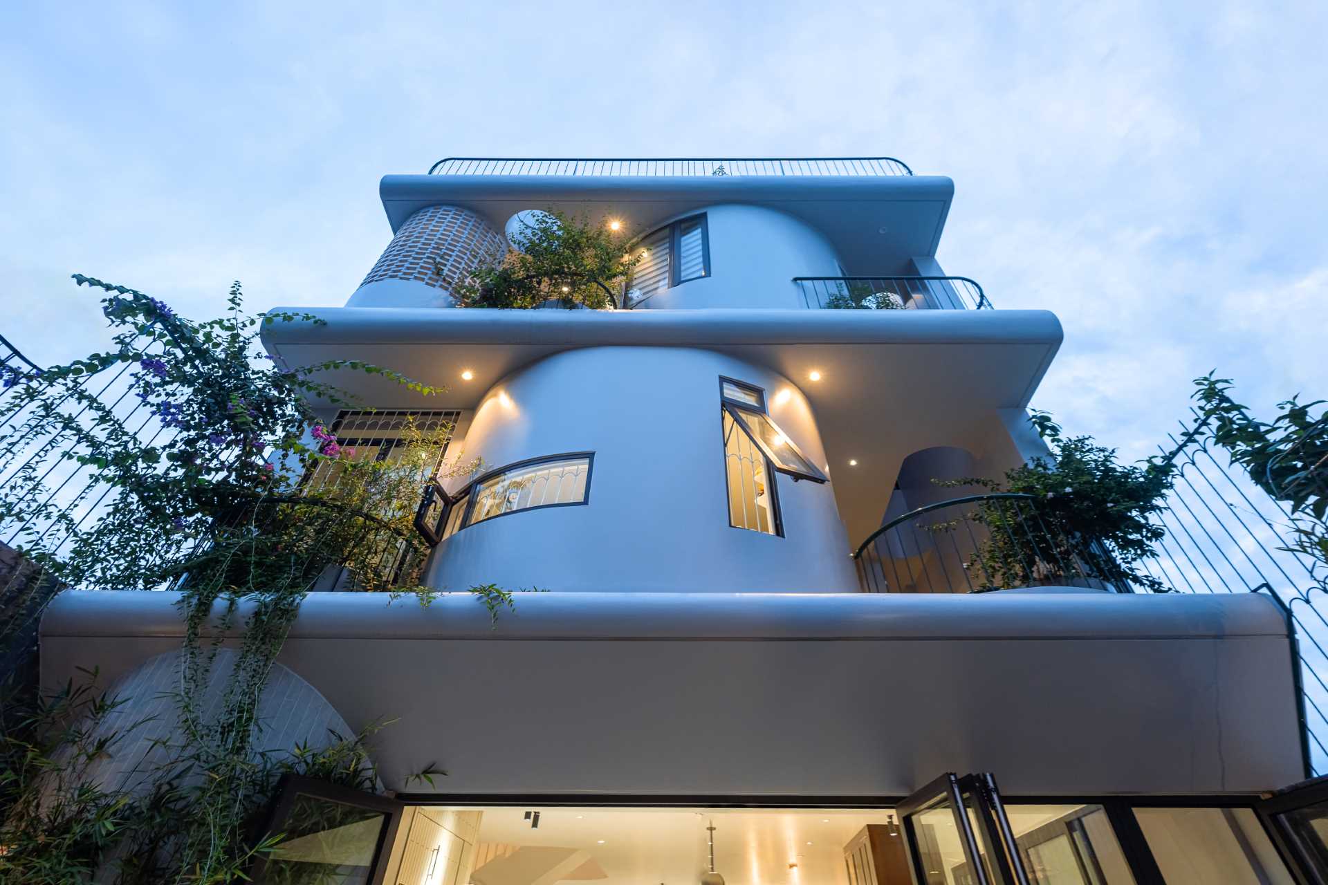 At night, exterior lighting highlights the various design elements of the home, like the plants, glass blocks, or the soft curved architectural volumes.