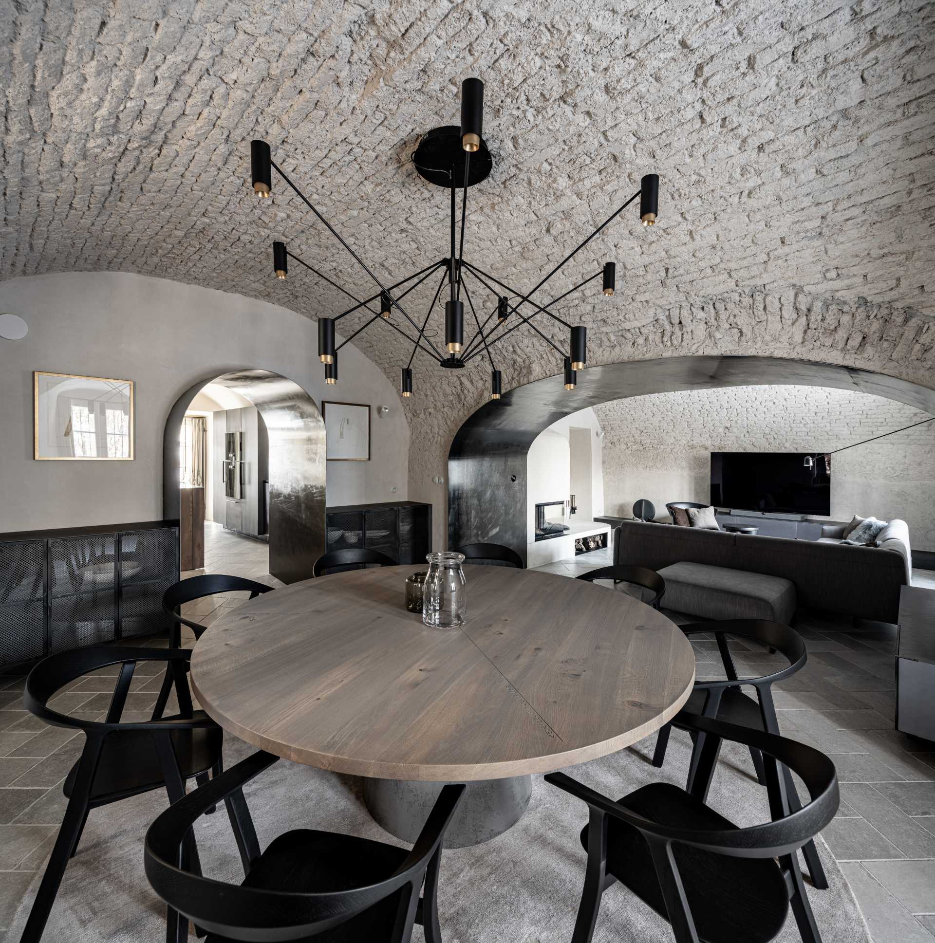 This dining room is dominated by a large circular dining table with engraved coordinates that record important life moments of the clients, while a dominant multi-armed chandelier is placed above the dining table.