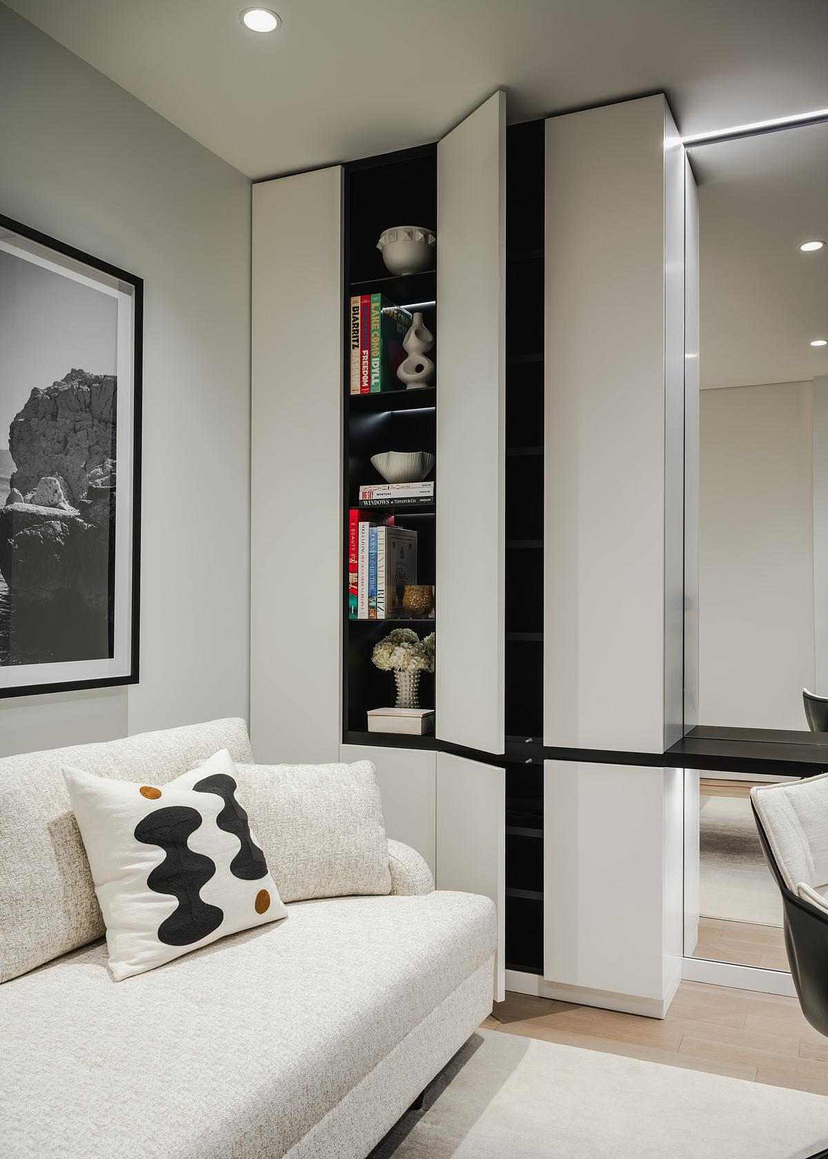 The interior design of a home office. with a couch, built-in desk, textured black leather panels, a mirrored wall, and plenty of storage cabinets.