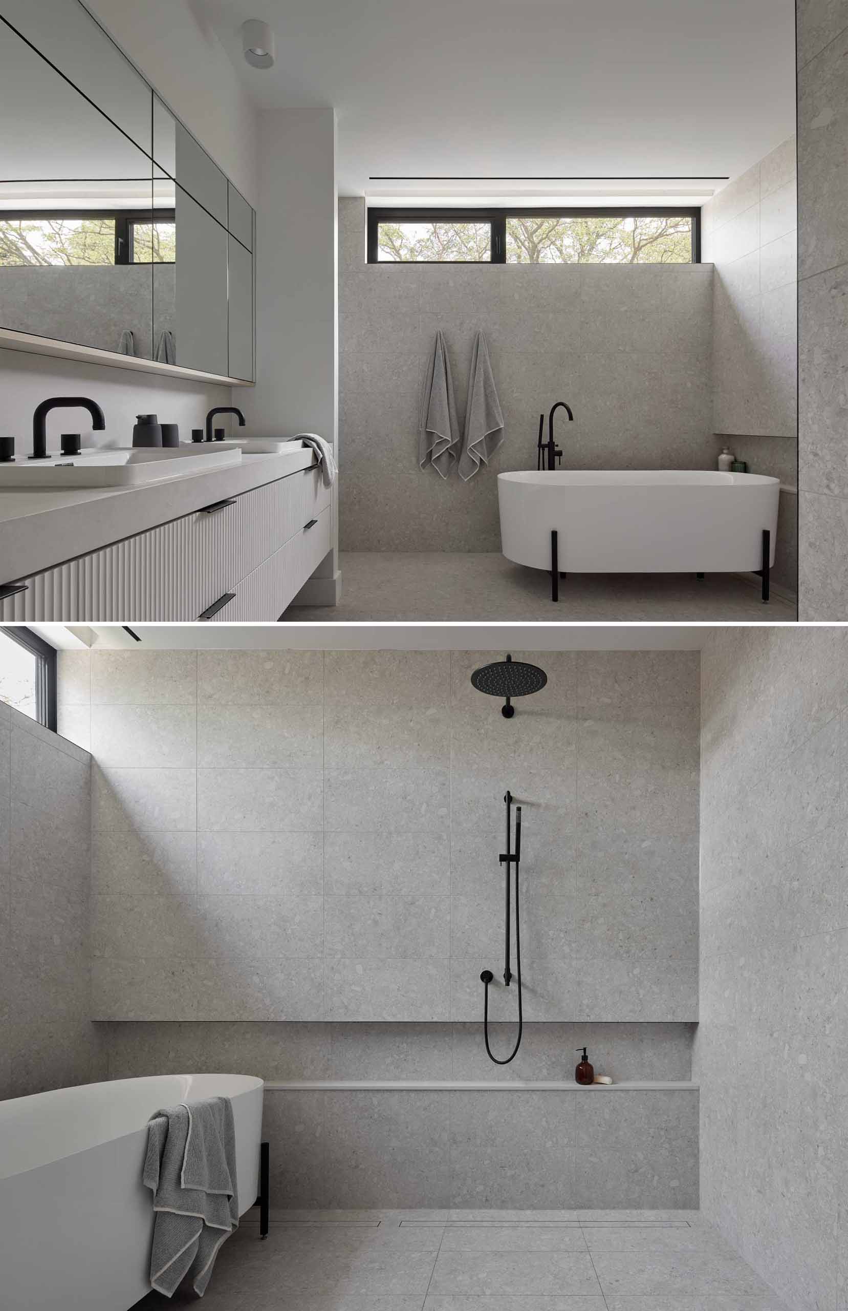 This modern primary en-suite bathroom has a double-vanity, a freestanding bathtub, and a shelving niche that runs the width of the wall.