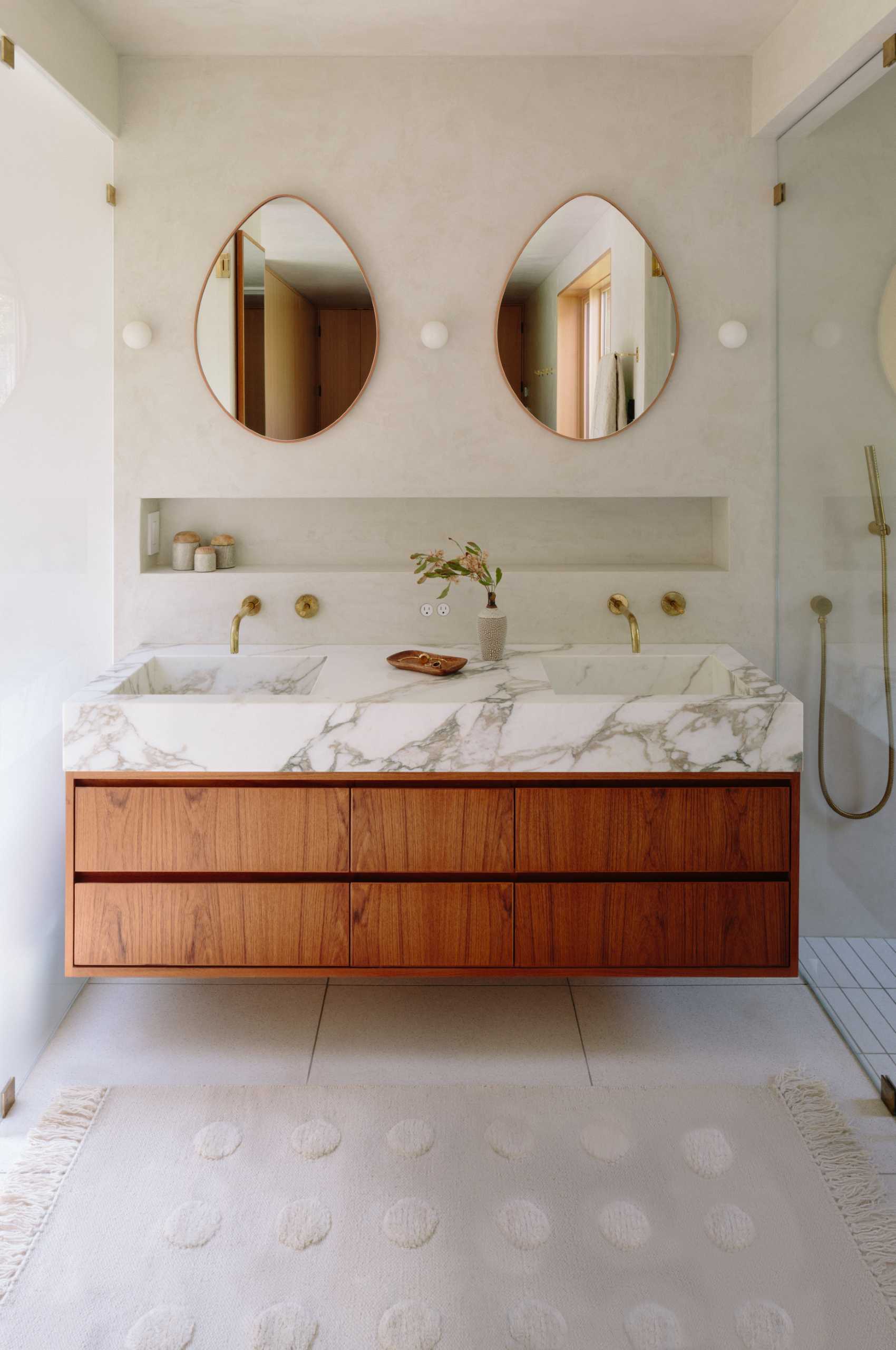 A bathroom in a renovated mid-century modern house has a double vanity with a shelving niche above it.